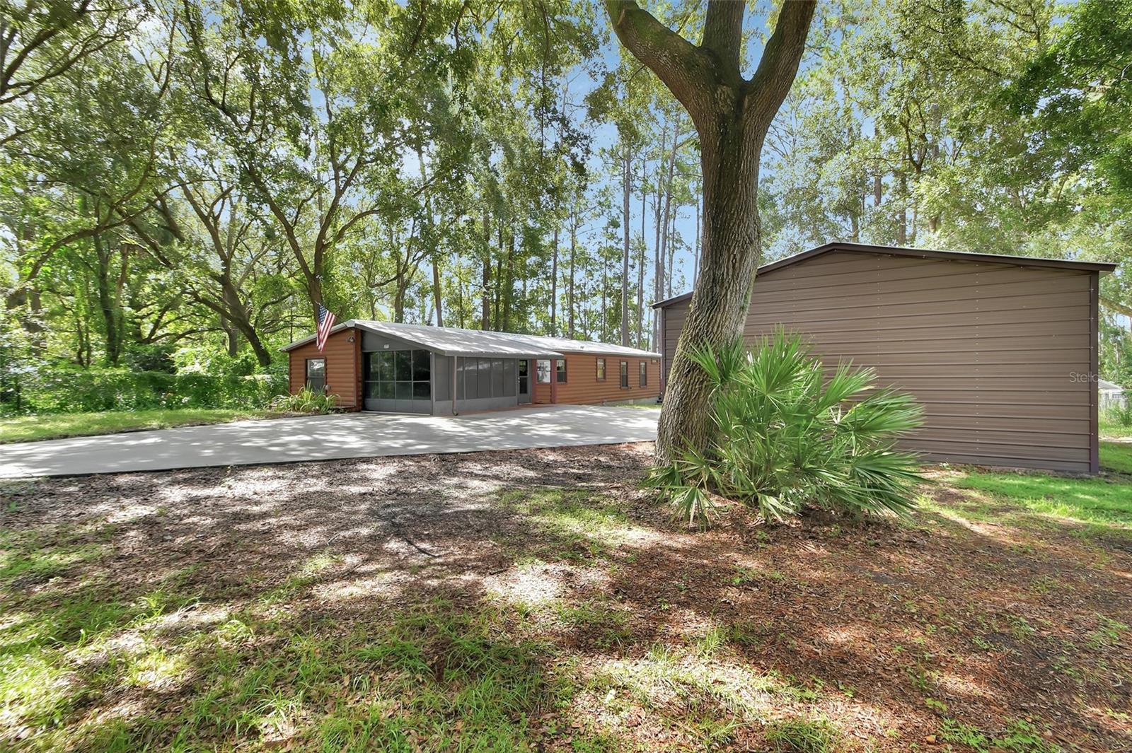 Presenting a well-maintained two-bedroom, two-bathroom residence situated on Lake Kathryn in Paisley, Florida. This property provides tranquil living with picturesque views of the spring-fed, fish-filled lake. The expansive back porch includes a spa/jacuzzi and offers access to a long boardwalk leading directly to a lakeside dock. A private boat ramp is also located on the premises for convenient watercraft launching.
In addition, the property features a spacious, recently constructed detached metal building suitable for storage or accommodating a car collection. All metal roofs, including those on the home and outbuildings, were replaced in 2024, ensuring long-lasting durability. This property is ideal as either a primary residence or a second home, with convenient access to the 429, SR 44, and SR 42, as well as easy routes to DeLand and surrounding areas. Seller is offering a home warranty up to $750.