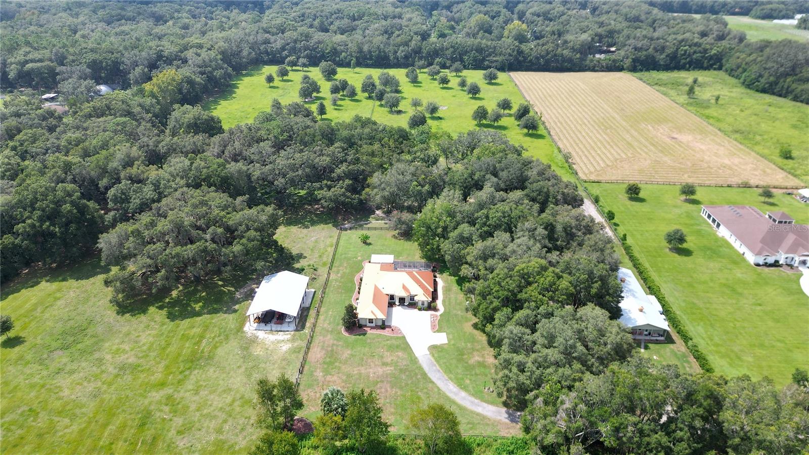 Discover this exceptional, turnkey, nearly 24-acre horse farm located in the Farmland Preservation district. Just 6 minutes from the World Equestrian Center (WEC) and 8 minutes to HITS, this property is a rare find. Upon arrival, you are greeted by beautiful aluminum privacy gates that open to reveal this exclusive estate. The turnkey stucco house features an open floor plan with 10 ft ceilings in the main living area, hardwood floors, high-end finishes, and a gourmet kitchen equipped with natural gas appliances. The family room is a highlight of the home, offering a contemporary linear fireplace and an illuminated tray ceiling that adds a layer of sophistication and ambiance. This space seamlessly transitions to the covered outdoor kitchen, which is a culinary enthusiast's dream. Complete with a deluxe grilling station, granite counters, a beverage fridge, and a prep sink, it's the perfect venue for entertaining and enjoying the property's scenic views. The primary bedroom is a sanctuary of comfort, boasting another linear fireplace, a tray ceiling for added elegance, and luxurious accommodations. The en suite primary bathroom features dual sinks, a luxury freestanding tub, a HUGE double walk-in shower, and a walk-in closet with laundry hook-ups, ensuring convenience and sophistication. Relax in the screened-in lanai with a pool and hot tub, finished with brick pavers, surrounded by majestic live oak trees.
HORSE FACILITIES
The estate is fully fenced and cross-fenced, providing a secure and picturesque setting for horses. The horse barn includes six stalls (with the potential for more), a climate-controlled tack room, a bathroom with washer and dryer, hot & cold water in the wash stall area, and a separate feed room. The property's equestrian facilities are further enhanced by a round pen and a 20 meter x 40 meter arena for comprehensive training and 40 X 60 barndominium.
An attached 2-bedroom, 2-bathroom apartment with high-end amenities offers additional income potential or comfortable guest accommodation. This high and dry estate combines the privacy of a secluded flag lot location with the convenience of proximity to essential amenities.
Ideal for those seeking unparalleled quality, privacy, and location, this horse farm and its expansion potential seamlessly blend luxury living with the best of equestrian lifestyle, enhanced by the ultimate outdoor living features.