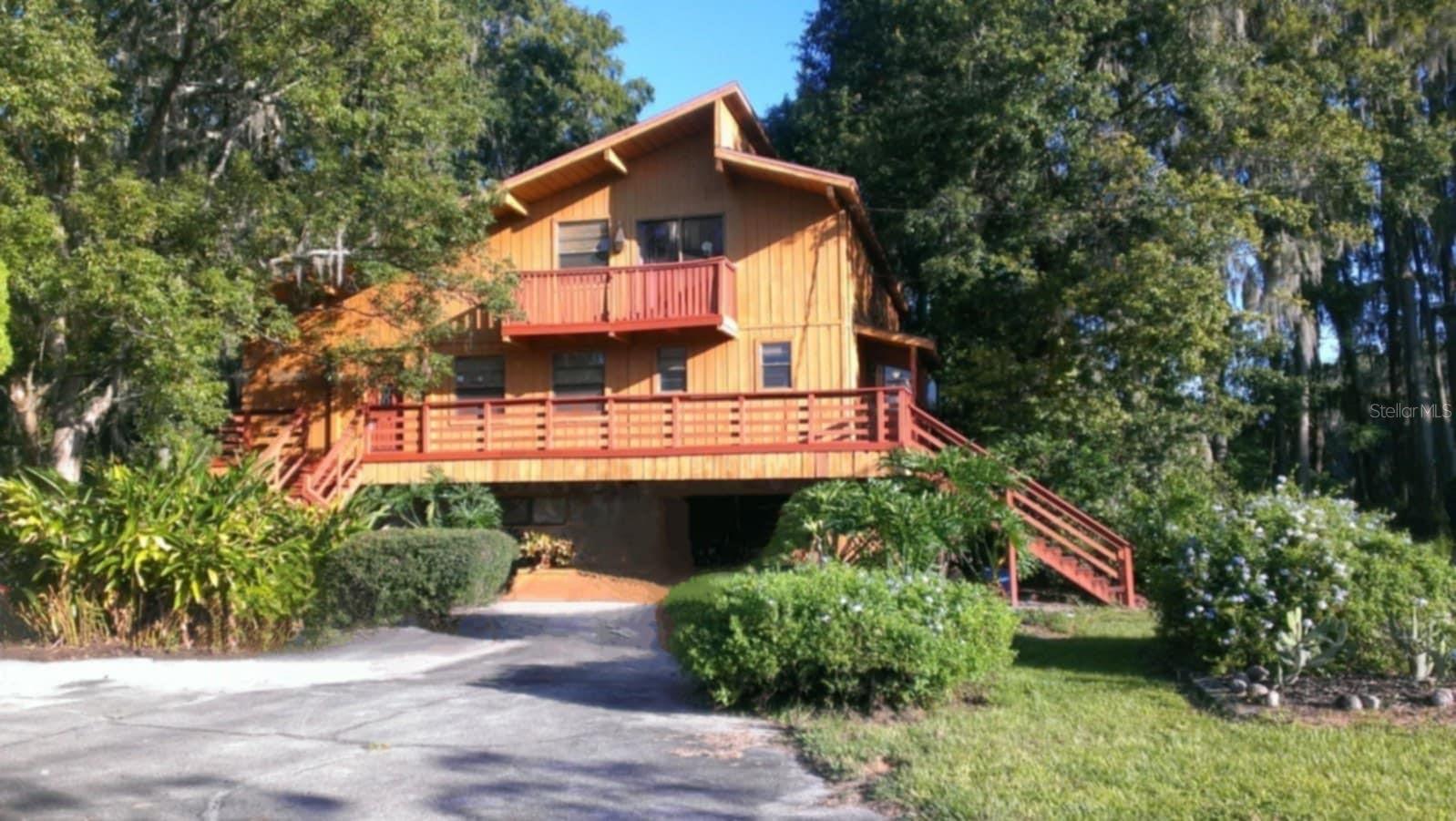 Exceptional Lakefront Estate on Nearly 4 Acres with 350 Ft of Freshwater Shoreline. This rare retreat spans 2 adjoining parcels and offers a unique blend of natural beauty, spacious living, and versatile functionality. Horses allowed. No HOA. No flood insurance required. The primary residence is a striking 3-story contemporary home (built in 1981), designed to capture panoramic views of the lake from every level. Inside the main home, you'll find 3,463 sq ft of living space and a total of 5,472.70 sq ft under roof. The attached 2-car garage features a rare drive-through design, allowing easy access straight through to the backyard and into Little Lake Hobbs, which connects to the 61-acre deep-water Lake Hobbs. The 2nd parcel, located at 417 Trout Lake Ct, includes a 1,280 sq ft concrete block garage with two 8-ft doors, 10-ft ceilings, 4-post car lift, a half bath, extra footings, and wooden trusses—constructed with potential for upward expansion. Whether you're seeking a full-time residence, a multi-generational compound, or a unique investment opportunity, this lakeside estate is truly rare and remarkable. The 2nd floor is the heart of the home, featuring a great room with vaulted ceilings and Canadian cedar beams, a floor-to-ceiling stone fireplace with gas logs, an eat-in kitchen, a dry bar with cedar shelving, a dining area, and an atrium breakfast nook. Additional features include a walk-in closet at the entry, a rec room, a half bath, and a laundry room with a built-in ironing board. The ground-level in-law suite has its own entrance, full kitchen, laundry room, walk-in closet, bathroom with walk-in shower, and a living area with sliding doors that open to a covered patio, koi pond, and lake views. Upstairs, the 3rd floor hosts the primary suite and 2 guest bedrooms. The primary suite includes a large walk-in closet with a window and exhaust fan, a jetted tub encased in glass, a walk-in shower, bidet, high-rise commode, and vanity. The guest bathroom features a steam bath with a Jacuzzi tub. Outdoor living shines with a screened patio and 6-person Jacuzzi, and a 2nd-level balcony with elevated lake views connected to the 3rd-level deck via a circular staircase. A metal-roofed pole barn and multiple parking pads accommodate boats, RVs, or equipment. A Ford tractor with bush hog is included (needs repair). The estate is fenced with electric front fencing and features a pecan grove, Bahia pasture, avocado, cherry, papaya, and mulberry trees, as well as grapevines. A cement bench offers shaded lake views. Additional Features: Outdoor lighting, Well-fed irrigation, 300-ft deep well with 3HP submersible pump, 100-ft backup well, Propane instant water heater and attic fan on the third level for energy efficiency. Water enthusiasts will love the covered boat dock with sundeck, boat lift, launch, outdoor lighting/electric outlet, and stairway access from the home just a few feet away. Conveniently located just 20 minutes from downtown Tampa, with easy access to the Suncoast Pkwy, Van Dyke Rd, and Dale Mabry Hwy. Commute times: 21 mins to Tampa VA Hospital, 22 mins to Tampa Airport, 36 mins to MacDill AFB, 20 mins to USF, and under 1.5 hrs to Orlando Airport.