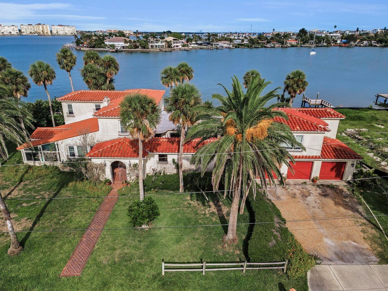 Constructed in 1935 by the Redington family, this Spanish-style residence showcases stunning architectural details throughout, including intricate moldings, high ceilings, and grand formal living areas. The spacious side yard provides ample room for outdoor recreation. The property boasts 180 feet of waterfront access, a private dock, a pool, and incredible water views, offering an ideal setting for those seeking a waterfront lifestyle.
Approximately 3,865 square feet of living space in this formerly stately home, it offers five bedrooms and four and a half bathrooms. The main house features four bedrooms and three and a half baths, with the primary bedroom and bath located on the first floor. Located above the 3 car garage is the one-bedroom, one-bath guest suite.
Unfortunately, the first-floor living spaces did sustain water damage, but the second-floor areas and guest suite remain unaffected, providing a unique opportunity for a discerning buyer to restore this home to its former grandeur. The existing three-car garage and in-ground pool further complement the property's impressive amenities. The covered portico is a stunning place to welcome guests or simply provide covered entertaining area as it is separated from the two additional outdoor living spaces.
Situated on beautiful grounds, this home is ready to be transformed into a stunning showcase, catering to those who can envision its full potential. The owners are hoping for a buyer who can embrace the vision of what this remarkable property once was and work to bring it back to life, however it is plotted for 3 lots so that you could truly remake it your own if desired.