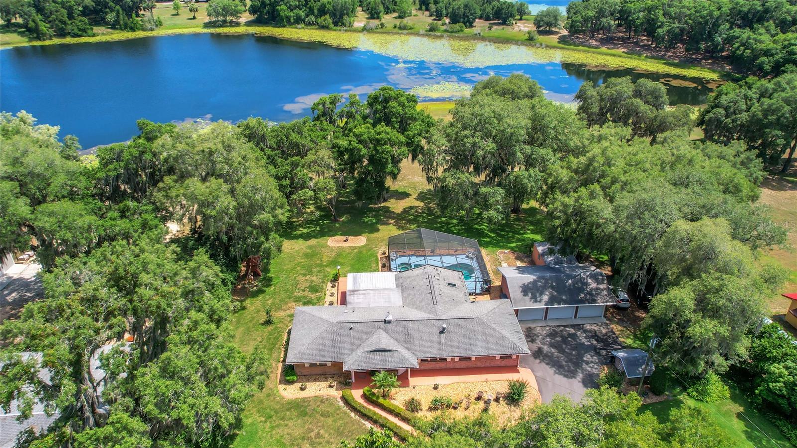 Beautiful breathtaking views of an enchanting Lake await you on this Waterfront / Pool Home with a separate 3 Car Garage situated on nearly 2.5 acres giving you a country feel but just minutes away from shopping! This home is an Entertainer's Paradise! The birdcage pool / jacuzzi area is quite spacious allowing plenty of room for sunbathing, tables, chairs and a BBQ. Adjacent to that is your outdoor deck which has a beautiful railing and stairs leading into the beautiful yard. You can gather in the screen enclosed lanai area or the indoor Florida Room. All of the forementioned areas have the gorgeous views of Lake Hermosa. Inside, there is a Bonus Recreation room with a pool table and a long wet bar built for a crowd. The oversized driveway with a parking pad and overflow parking area plus the 3 car garage provides plenty of guest parking. This 2608 (under heat/air) square ft home features 3 bedrooms, 2 baths, a split bedroom floor plan, ceiling fans, and a wood burning fireplace! The spacious master suite boasts a window seat overlooking the pool and lake, a hand crafted gorgeous barn door, a glass enclosed walk-in shower, a large soaker tub, double sinks and a 7x8 walk-in closet. This is quite a unique house, one Not To Be Missed. A few other updates include: architectural roof replaced in 2013, drain field replaced in 2019, and chlorine pool resurfaced in 2016. This home has a hook up for a generator. You are conveniently located to restaurants, shopping, grocery stores and The Villages offering nightly entertainment. Please call for your private showing before this resort style entertainers paradise is gone.