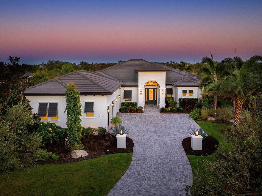 Warm, inviting, private – the words that best describe this stunning John Cannon home in The Lake Club of Lakewood Ranch. The house is set back from the road on .42 acres, bordering a lush Florida preserve. This 2019 Talia floor plan has had every detail carefully chosen using natural materials- brick feature walls, exposed wood beams and wood-look porcelain plank tile flooring.  Meticulous landscaping and specimen trees line the curved paver driveway. The covered front landing, with an impact glass door, opens into the spacious, high ceiling foyer. The entertaining areas are positioned to highlight the endless conservation views. This protected preserve is home to deer, heron and sandhill cranes. The central Great Room is designed for comfortable gathering and features a custom tray ceiling, entertainment and display niches, brick feature walls and sliding glass doors to the lanai. The Dining Room, with its exposed wood beams and disappearing corner sliders, has an open flow into both the indoor and outdoor kitchens and is functional and beautiful for both casual and formal dinners. The paved lanai is a peaceful place to enjoy the view. It is furnished with designer lighting fixtures, a well outfitted outdoor kitchen and a heated, Gunnite/Pebble tec saltwater pool and spa. The lanai is secured by a colonnaded screen enclosure. Behind the lanai is a beautifully landscaped backyard space. The same natural finishes, brick walls and wood beams extend into the chef’s kitchen. The kitchen features a wall of windows that let in natural light throughout the day. The large central island has a beautiful, Cambria quartz countertop. The kitchen is built for entertaining, with Chef quality stainless steel appliances including a Bluestar professional-grade 6 burner range, 48” Sub Zero refrigerator, double Bosch ovens, two Bosch dishwashers, ample storage in sleek modern cabinetry that extends to the ceiling and a spacious walk-in pantry with custom shelving, hidden behind cabinet doors. Enjoy the view of the pool, lanai and preserve from the relaxing primary suite with designer feature wall, plush carpeting and dual walk-in closets with custom shelving and ample hanging space. The same attention to detail is evident in the spa-like bathroom with designer wallpaper, long vanity, large walk-in shower, modern cabinetry and fixtures. Guests will enjoy the two en-suite guest bedrooms with walk-in showers and designer lighting. This open floor plan includes a large bonus “club” room with sliding glass lanai doors, powder room, huge storage closet with custom shelving, office space with built-in desk and laundry room with extra cabinetry. The custom, 3-car side-loading garage is an enthusiast’s dream. 3 8000-lb capacity Atlas vehicle stackers expand the space to accommodate up to 6 vehicles. Vehicles up to an 80” SUV can easily fit under a stacker. A 2022 mini-split AC unit and Icynene spray foam insulation maintain a constant temperature. The vehicle stackers can also be used as extra space for temperature-controlled storage. In addition to John Cannon’s quality construction, this home has impact doors and windows though out, landscape lighting, 2020 Kohler whole-house generator, 2022 Culligan whole-house reverse osmosis water filtration, Clare Home automation with cameras, Sonos surround sound, surge protector and other security features. The Lake Club is a premier, gated community with a Grande Clubhouse, restaurant, pool, tennis, pickleball and more.