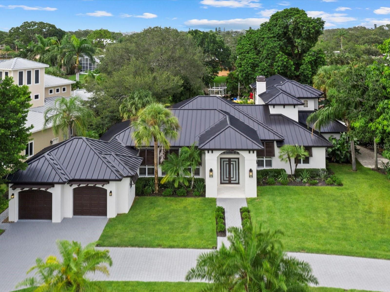 Welcome to one of Sarasota’s most coveted waterfront communities—Coral Cove, where homes rarely become available and even fewer offer the exceptional combination of elevation, design, and location that this one does. Perfectly situated on a spacious 0.59-acre corner lot directly across from the private neighborhood park and boat ramp, this British West Indies-style home has been reimagined through extensive renovations from 1999–2004 and again in 2023–2024, giving it an effective year built of 2009. This fully remodeled 4-bedroom, 3.5-bathroom residence spans over 5,000 square feet and sits high and dry above sea level, with no flood damage during recent hurricanes. With a new metal roof, brand-new impact-rated windows and doors, and solid core shaker-style interior doors, no detail was overlooked. Step inside to the tall 10-12 foot ceilings, engineered hardwood floors, and tons of natural light coming through the French doors and large sliders that lead to your private outdoor oasis. The centerpiece of the home is the chef’s kitchen featuring Café Series appliances, a fluted range hood, Dolomite countertops, waterfall-edge peninsula seating, walk-in pantry, and soft-close white cabinetry, all opening seamlessly to the living and dining areas. This home offers two true primary suites, choose between a luxurious ground-floor retreat or a private upstairs sanctuary. The upper-level suite boasts a spa-like bathroom with a freestanding tub, dual vanities, walk-in shower, and a massive walk-in closet. An additional ensuite bedroom and fourth bedroom/office are thoughtfully positioned on the main level. Outside, enjoy a large pool, limestone decking, lush landscaping, and a brand-new dock with a floating jet ski pad, great for waterfront entertaining. With no HOA and your own private boat launch just across the street, this home is tailor-made for the Florida coastal lifestyle. All this is just minutes from world-renowned Siesta Key Beach, as well as Sarasota’s vibrant shopping, dining, and cultural scene. If you’ve been searching for a luxury waterfront rental West of the Trail that checks every box—style, safety, size, and serenity—this is it.
