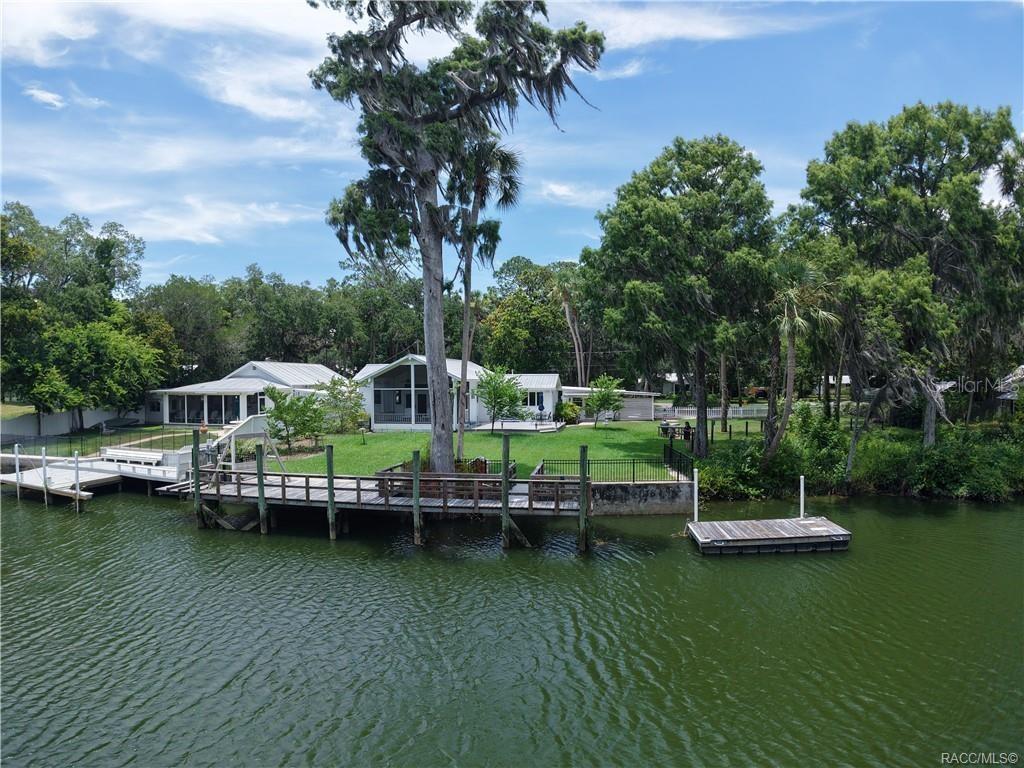 Charming Riverside Retreat with Additional Lot for Ultimate Privacy – Yankeetown, FL. Welcome to Old Florida living at its finest! This beautifully maintained 2-bedroom, 2-bathroom home is nestled directly on the stunning Withlacoochee River and is being sold together with an adjoining 0.39-acre lot, providing a combined 0.71 acres of serene privacy. Located on prestigious Riverside Drive in the heart of historic Yankeetown, this unique property is just a short boat ride to the Gulf. Originally built in 1930, this character-filled home features wood floors, plantation shutters, an attached carport, boat dock, boat lift, and a detached studio/office—perfect for creative work or quiet reflection. The metal roof adds both charm and durability, while the lush landscaping creates a peaceful, park-like setting. The additional lot includes a 34’ x 12’ covered carport with a 16’ x 10’ storage building, ideal for a workshop or extra storage. Plenty of room for your RV, boat, golf cart, or side-by-side—NO HOA means you can truly live the Florida lifestyle your way. Whether you're fishing, boating, or simply enjoying the natural beauty of the Nature Coast, this riverfront retreat offers it all. Don't miss the chance to own a piece of Yankeetown’s timeless charm—some of the best fishing in Florida is right at your doorstep!