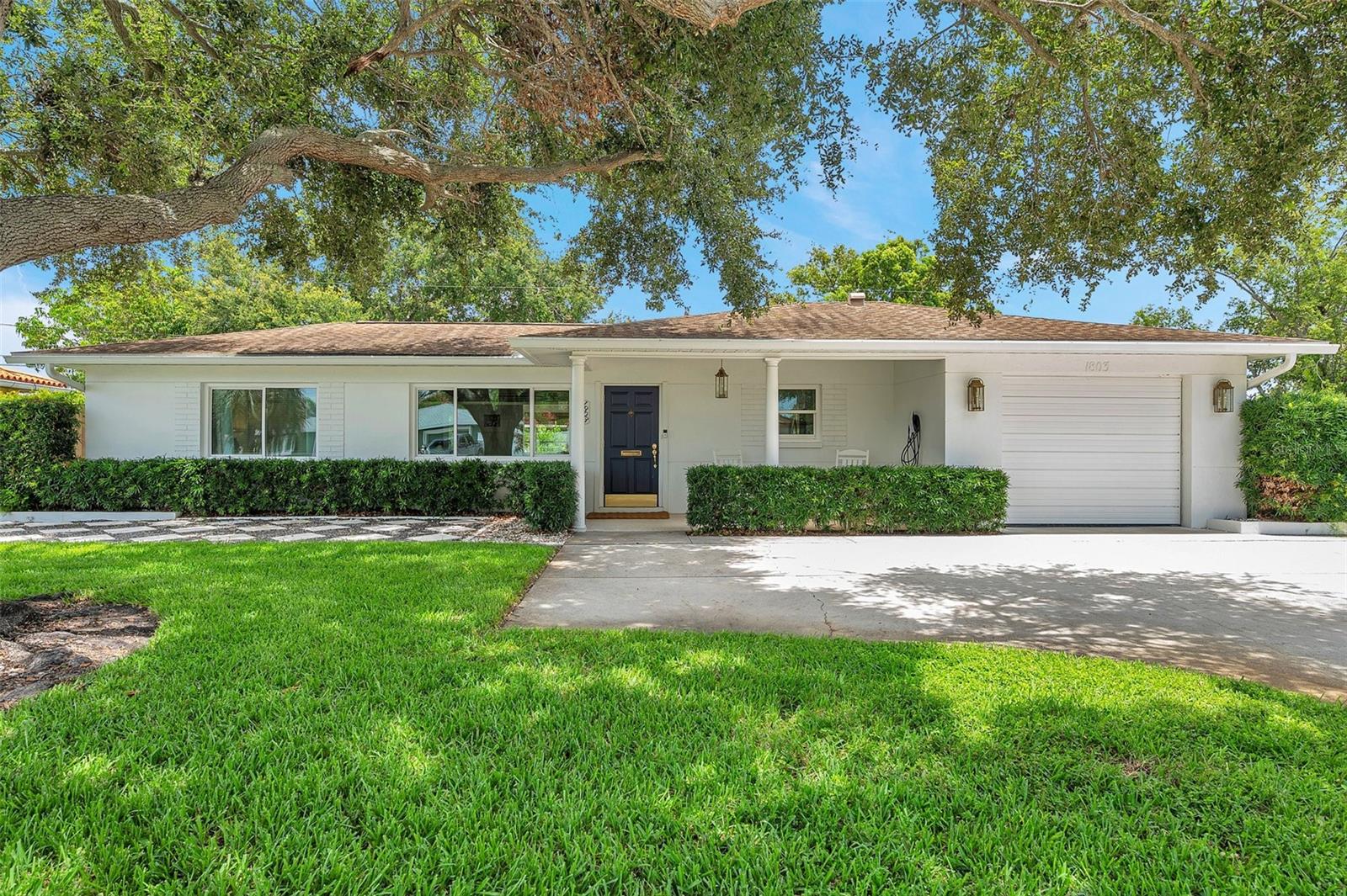 Welcome to this fully remodeled 2-bedroom, 2-bathroom block home with 1,421 sq ft of living space, a 1-car garage, and timeless coastal charm. Situated high and dry on a quiet street with no flood zone concerns. A welcoming front porch and a large, beautiful shade tree add charm and curb appeal to the front yard. Step inside to an open-concept layout with soft coastal tones, recessed lighting, and luxury vinyl plank flooring throughout. The spacious living room features a shiplap accent wall, and the primary bedroom also includes a stylish shiplap feature for added character. The updated eat-in kitchen is a showstopper with a large center island, propane gas range, ceiling-mounted hood, apron-front farm sink, subway tile backsplash, granite countertops, shaker cabinetry, bar seating, and an undermount microwave. A sun-drenched bonus room at the rear offers formal dining or flex space, complete with a dry bar, wine cooler, and access to the expansive travertine tile patio and beautifully landscaped, fenced backyard with ample room for a pool. The main bathroom boasts a double vanity and large LED mirror. The garage includes the original second bathroom (not in heated sq ft), providing potential to convert into an owner’s suite. Additional highlights include impact-rated windows and doors, Tesla EV charger, and fresh interior/exterior paint. Just minutes to I-275, shopping, dining, beaches, and vibrant downtown St. Pete.
