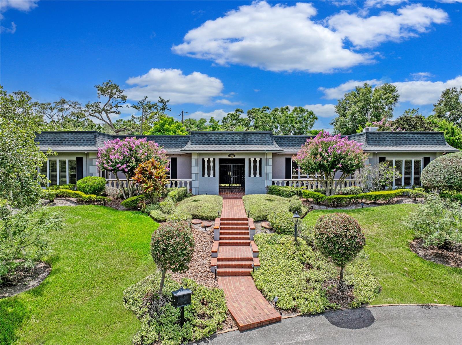Welcome to this stunning French-inspired architectural masterpiece tucked away in the sought-after Scott Lake area, nestled on a peaceful cul-de-sac with breathtaking views and deeded lake access. As you walk up the impressive, solid brick walkway, you’ll be drawn in by the lush landscaping and the timeless appeal of the brick terraces. This home invites you in through a stately double-door entryway, where elegance and craftsmanship are immediately on display. From the impressive architectural details to the plantation shutters throughout, this remarkable 4-bedroom, 3.5-bathroom home is a true showcase of luxury, sophistication, and attention to detail. Inside, the foyer is stunning, featuring elegant marble tile and authentic grasscloth wallpaper, which sets the tone for the richness throughout. Just off the entry, leaded-glass decorative windows reveal a charming step-down entertaining room and lead into the formal dining room. The home features Brazilian cherry hardwood floors throughout most of the living spaces, complemented beautifully by neutral tones and accented with crown molding in nearly every room (excluding the bedrooms and hall closets). At the heart of the home, the open-concept living area is anchored by a gourmet chef’s kitchen, thoughtfully designed with both elegance and function in mind. The kitchen showcases an oversized quartz waterfall island with a prep sink and microwave drawer, two-tone custom cabinetry, and a custom pantry concealed within the cabinetry. It also includes pull-outs on all drawers, a quartz backsplash, and top-tier stainless steel appliances, including a Sub-Zero refrigerator. The attached butler’s pantry, complete with a second Sub-Zero refrigerator, elevates the home’s entertaining functionality and daily comfort. This home offers abundant storage, and every inch of this residence has been thoughtfully designed. Retreat to the private living quarters, where the spacious master suite provides serene lake views, a generous walk-in closet, and a beautifully updated en-suite bath with granite counters and a walk-in shower. Two additional bedrooms feature en-suite bathrooms, and the fourth bedroom is suitable for use as a guest room or a dedicated home office.
Step outside to the screened-in lanai, an entertainer’s dream, where large floor-to-ceiling windows from the family room provide a seamless view of the sparkling, saltwater heated pool. The home also features two new A/C units and a whole-home generator, ensuring comfort and security year-round. With its incredible layout, timeless upgrades, and elegant lakeside setting, this home is truly beyond words—you simply have to schedule a private showing to experience it in person.