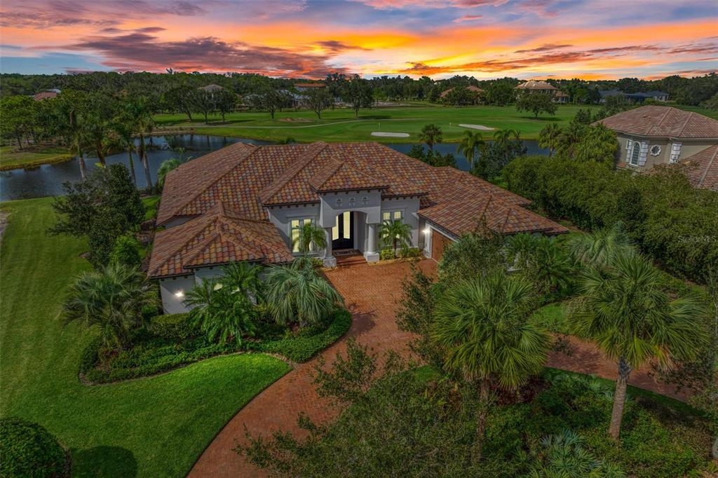 Magnificent lake and golf course views welcome you home to this gorgeous custom estate, situated on one of the best homesites in the acclaimed Founders Club. Through the 24/7-guarded security gate, an oasis awaits - where homes are nestled amongst hundreds of acres of untouched nature preserves, ancient oaks, sparkling lakes, and a prized Robert Trent Jones, Jr. golf course. This enchanting home is ideal for those who appreciate quality construction and desire a private estate home and location that cannot be compromised. Timeless exterior with semi-circle driveway, lush landscaping, 4 car garage and custom iron doors. Once inside, this sunlit single-story home will capture your heart. The elegant floorplan flows graciously and is centered around an ample great room and striking gourmet kitchen. You'll find tall ceilings with tray and crown details, abundant new custom built-ins with fireplace features, beautiful sandy colored oak wood floors in all main areas, and new plush high-end carpeting in all bedrooms. Hurricane-impact sliding glass doors and windows showcase stunning views and provide a light & bright ambiance throughout this cheerful residence. The show-worthy kitchen offers custom cream cabinets, gorgeous 'Taj Mahal' natural quartzite stone counters, and professional-grade Wolf and Sub-Zero appliances. This home lives large, offering sizable main living areas and spacious en-suite guest bedrooms for optimal moments of solitude, when desired. An expansive owner's retreat is a sanctuary with beautiful built ins, separate custom dressing areas, large windows, access to the lanai, and a luxurious bathroom with smart storage, double vanities, and abundant natural lighting. A lovely den with glass French doors plus a generously sized bonus room with built in fridge completes the home. The intelligent design is sure to please those who crave contemporary open spaces for gathering with friends and loved ones as well as the opportunity for privacy, which is provided by separate guest wings. The interior transitions seamlessly through tall pocketing sliders to the incredible outdoor living area. A large, covered lanai and regal colonnade enclosure with new screens frames spectacular views of paradise and offers a heated saltwater pool with infinity spa and outdoor kitchen with Wolf grill and refrigerator. Extensive upgrades completed in 2021/2022- including: whole home interior/exterior paint, new landscaping and landscape lighting, 3 entertainment-built ins w/ 3 Dimplex fireplaces, new mudroom cabinets, Culligan water treatment and reverse osmosis, hard-wired security cameras, epoxy floors, and much more. Live the dream and come home to this amazing retreat. The highly desirable Founders Club is a gated enclave of 262 custom private estates. The neighborhood boasts character and is located in non-flood-zone X, with easy access to downtown (9 miles approximately) and award-winning world-class beaches. Mere minutes to the new LakeWood Ranch shops and restaurants of Waterside, Sunday farmer's market, polo fields, Publix grocery store, parks, trails, UTC, area attractions. Golf or social membership separate and not required. Har-Tru tennis courts, fitness studio, restaurant with veranda, social activities and clubhouse for members. Schedule your private tour today to see this remarkable home.