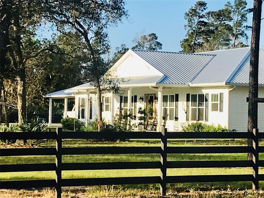 White farmhouse built in 2018 on 10 acres in Edgewater on paved road only 13 miles to the beach and 6 miles to the intracoastal.  Entering the property through the 4 board wood fence and stone columns with gate you will see the charming home with matching barn, and carport. The custom built 3 bedroom 2 bath home with study and open floor concept offers wide plank pine wood floors, cathedral ceilings, 8' doors throughout, and tons of windows adding lots of natural light.  The kitchen is a chef's dream with luxury appliances including a 6 burner GE Monogram stove with griddle, double oven and hood ventilation system, GE Monogram dishwasher, and GE Cafe refrigerator.  The granite topped center island has a prep sink, microwave, and seating area.  Look out over the back acreage while working in your oversized farm sink that sits in front of a triple window. Tongue and groove wood wall and ceiling in the study add warmth and character to this space and offer views of the front acreage.  The spacious master suite offers a garden tub, walk in shower, double vanity sink, toilet room, and very large walk in closet. Guest bedrooms and guest bath are located at the opposite end of the home with laundry room leading to carport.  Sit in your rocking chairs on the front porch and enjoy watching the sunrises in the mornings while having your coffee and relax on the back porch in the evenings while watching the beautiful sunsets.  Entertain your guests from the house or out at the barn where there is a stone bar, 1/2 bath, and TV.  The metal barn with pole barn construction has concrete floors, 3 overhead 12' tall doors, electric, water, and storage room that could be transitioned into man cave, office, or more.  Barn dimensions are 40'x56' with 14' walls and 14'x40' side porch and 14'x56' lean to off the back.  An additional lean to building and garden shed offer ample storage. Bring your toys, horses, and more and enjoy the country life!
