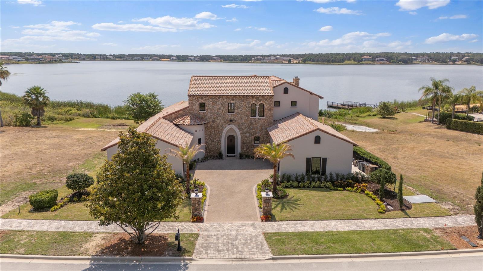Lakefront on Lake Siena, remodeled, pool and boat dock, come and start enjoying Bella Collina for all its best amenities starting with your backyard!! Nestled within a private, guard-gated community spanning 1,900 pristine acres, this home offers more than just a place to live; it embodies a lifestyle statement. Just remodeled inside and out and also new windows and doors added, this custom villa redefines elegance, boasting 4,319 square feet of unparalleled luxury. Step inside and be captivated by the soaring ceilings, architecturally interesting beams, and the allure of travertine and hardwood flooring. Every detail in this home is a work of art. The gourmet kitchen, complete with a gas cooktop and upscale Wolf appliances, seamlessly blends form and function. A double-sided gas fireplace sets the stage for both intimate family gatherings and grandiose entertaining, warming both the interior and the outdoor pool deck. Wine aficionados will appreciate the dedicated wine cellar, capable of holding up to 600 bottles. Retreat to the expansive private master suite, your haven away from the world. Outside, a sumptuous pool surrounded by travertine decking. With the lake as a backdrop, this space is perfect for soaking up the Florida sunshine or enjoying serene evenings watching the sun dip below the horizon. Located just minutes from Winter Garden, you'll have easy access to the freshest farmer's markets, fabulous dining experiences, and top-tier shopping. Despite its convenient location, this home is comfortably outside the tourist district, while still being within reach of theme parks, Cocoa Beach, the Gulf Coast, and the bustling city of Orlando. Indulge in a lifestyle of unrivaled luxury and convenience with amenities such as a golf course designed by Nick Faldo, tennis courts, a gym, resort-style pools, spas, and a 75,000 sq ft clubhouse featuring a private restaurant. Your every desire will be fulfilled in this exclusive community. Can be sold with the lot next door.. ( Vacant lot 409 ) sellers also own that. Call for more details.