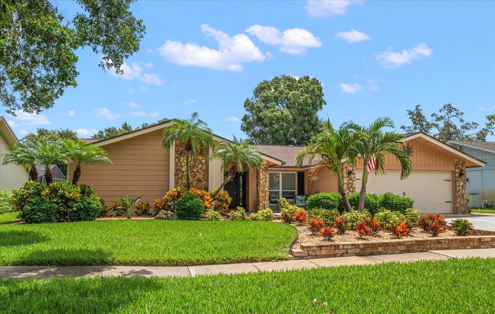 Nestled in the desirable and beautifully kept Clearwater neighborhood, Northwood West, this Campagna-built residence combines prime location with resort style living. Professional tropical landscaping and fresh exterior paint create head turning curb appeal, while a covered entry ushers you into a bright open floor plan and interiors awash in new luxury vinyl plank flooring, fresh paint and natural light. Designed for multigenerational flexibility, the open layout centers on a newly renovated eat-in kitchen flaunting white wood cabinets, quartz counters, stainless appliances, cove lighting, and an oversized island with a breakfast bar. Sliders leading out to the enclosed sparkling pool and a large covered porch, make entertaining family and friends effortless. The adjacent family room exudes coastal warmth with its stone fireplace, shiplap feature wall, and built-in coffee bar, while the formal dining room also spills out to the pool for seamless entertaining. A sunlit primary retreat enjoys private slider access to the lanai, a generous custom closet, and a spa inspired ensuite highlighted by a subway tiled walk in shower and furniture inspired vanity. Four additional bedrooms provide endless possibilities—including a separate in law or nanny suite—complemented by exquisitely renovated baths, one doubling as a convenient pool bath. Outside, a mature hedge and lush landscaping promises privacy, and practical upgrades abound: impact rated windows and doors, whole house generator-2021, gas tankless water heater-2021, indoor laundry, new epoxy coated garage floor-2025, all new lighting, new interior and exterior paint-2025, roof-2021, Main AC-2020, blown insulation in attic-2025, and more. Minutes to shopping, dining, two airports, and the Gulf’s world famous beaches, this turnkey tropical haven is the one everyone’s been waiting for—act fast before it’s gone!