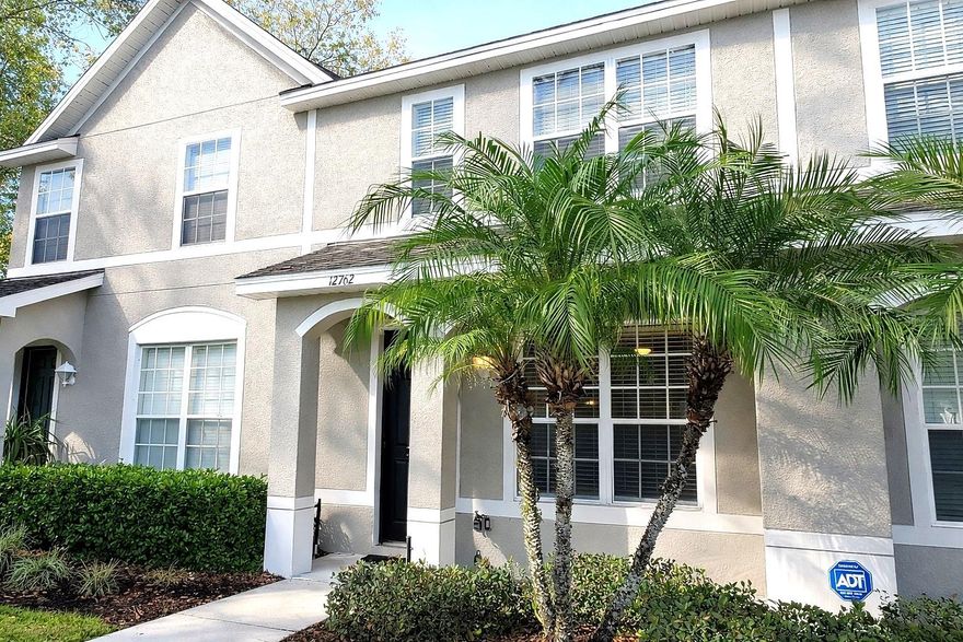Welcome to this charming 2-bedroom, 2.5-bath townhome in the desirable Country View community, centrally located in the heart of Tampa's Citrus Park/Carrollwood corridor. Built in 2005 with solid block and stucco construction, this two-story home offers 1,216 heated square feet of thoughtfully designed living space with a layout that balances comfort, privacy, and everyday functionality. The main level greets you with an open, airy floor plan featuring luxury vinyl plank flooring, soaring ceilings, and ceiling fans that keep things breezy year-round. The kitchen impresses with striking granite countertops, a double stainless steel sink with a sleek pull-down faucet, a breakfast bar for casual meals, and a full appliance package including range, refrigerator, dishwasher, and built-in microwave. A pendant light and chandelier add warm character to the kitchen and dining area, while sliding doors bring in natural light and provide access to the rear of the home. A powder room is conveniently located on the main floor for guests. Upstairs, both bedrooms are generously sized and each features its own private en suite bathroom — a rare and highly desirable layout that provides maximum privacy. Each room also has its own walk-in closet and ceiling fan. Laundry is conveniently located on the upper level as well. Out front, enjoy a covered porch framed by lush tropical landscaping and stately palms. Assigned and guest parking are just steps away, and the community's peaceful pond and mature greenery create a tranquil setting that's hard to beat. Located in Flood Zone X — no flood insurance required. The HOA covers water, sewer, trash, and exterior grounds maintenance, making this a truly low-maintenance ownership opportunity. Pets are welcome. Situated just minutes from the Veterans Expressway, 15–20 minutes to Tampa International Airport, and close to top retailers including Publix and Walmart, plus abundant dining, parks, and medical services. Easy access to everything the greater Tampa Bay area has to offer. Move-in ready and waiting for you — schedule your private tour today!