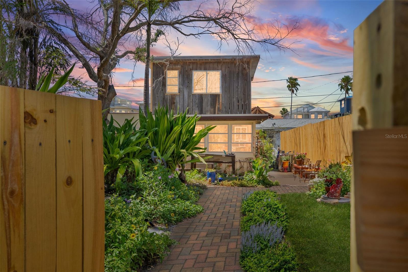 This charming 2-bedroom, 2-bath home on historic Sunset Beach in Treasure Island sits just two houses from the sand and offers picturesque water views right from the front yard. The City of Treasure Island determined this home was "not substantially damaged"! Perfectly positioned on the coveted south end of Sunset Beach, this property captures the essence of coastal living with a nostalgic original Sunset Beach-inspired ambiance. Hand-laid brickwork creates a welcoming courtyard, surrounded by mature, lush landscaping that creates the feeling of a private oasis. Inside, natural light fills the space, highlighting unique features such as concrete floors, wood ceilings, and hanging stained-glass windows. The primary level features a sun-filled dining area, kitchen, living room, guest bathroom, and a comfortable Florida room/guest bedroom—each space evoking the charm and character of Old Florida. Upstairs, the master bedroom has its own bathroom and it provides a private, comfortable retreat, completing the home's warm and peaceful presence. Watch nightly sunsets from your yard or stroll just one minute to the shoreline or the local dog beach. While the home did experience flooding during Hurricane Helene, it weathered the storm remarkably well thanks to its bottom level solid block construction with poured concrete walls (including interior walls). Recent updates include new electrical with 200 amp service, a new hot water heater, and a new reverse cycle mini split unit. Buyers are encouraged to contact the City of Treasure Island regarding the FEMA 50% rule before planning any remodels or new construction. Whether preserving the home’s historic charm or building new, this spacious 40x100 foot lot is one of the most desirable locations on Sunset Beach.