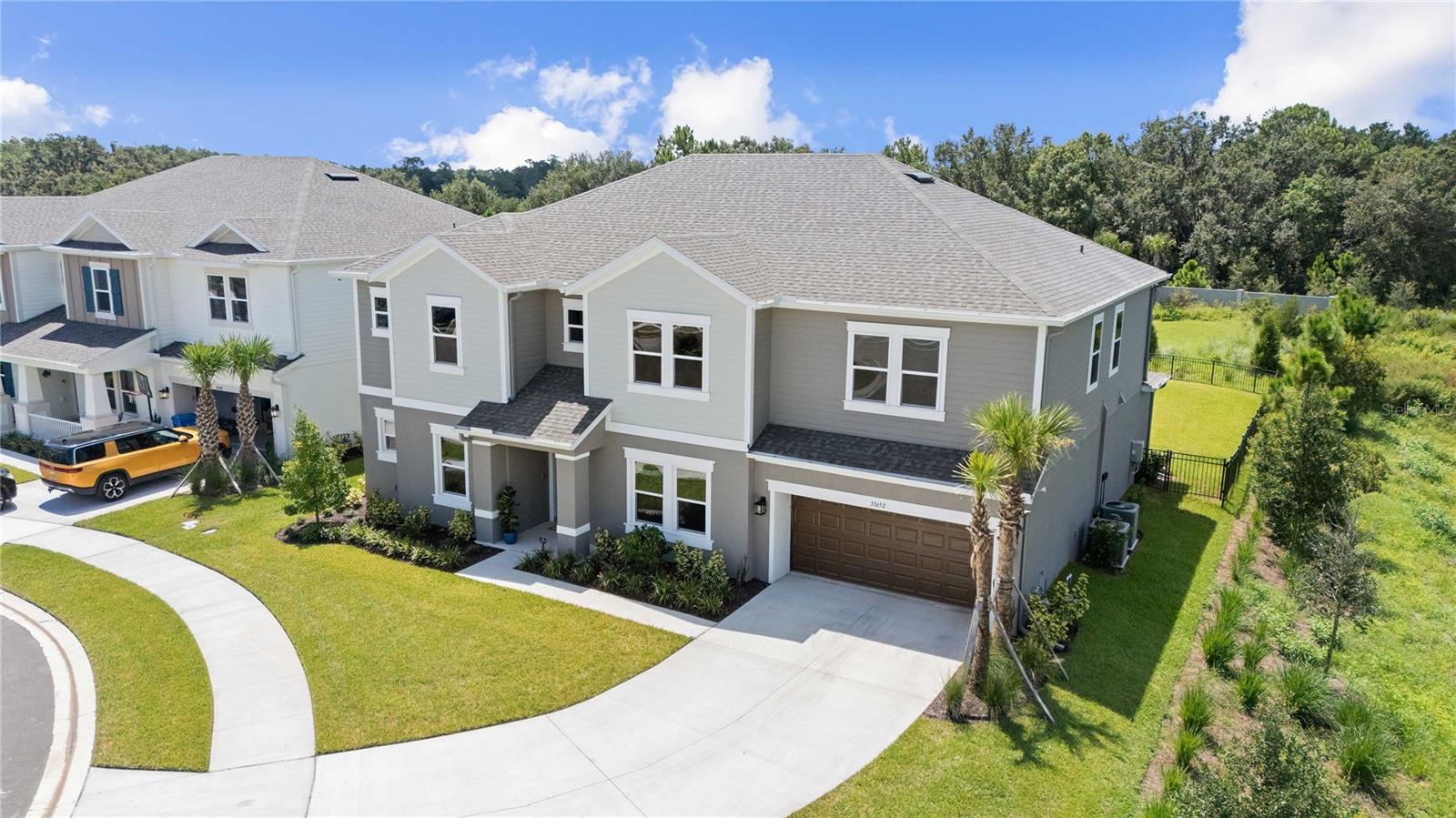 Prepare to be impressed by this stunning 6-bedroom, 4.5-bath home in the highly sought-after River Landing community. With an expansive 4,181 square feet, this energy-efficient property sits on a gorgeous private street, on a premium lot, at the end of a cul-de-sac, surrounded by ponds and conservation views, offering both beauty and tranquility. Step inside to discover the open floor plan, highlighted by soaring high ceilings and elegant 20 x 20 marble tile throughout the main floor. The heart of this home is the HUGE kitchen—featuring double islands, upgraded stainless high-end appliances, coordinating backsplash, a gas cooktop, an eat-in area, a breakfast bar, and a coffee bar/butler’s pantry with drink cooler—perfect for both daily living and entertaining. The home also includes a **tankless gas hot water heater**, ensuring endless hot water while enhancing energy efficiency. The primary suite on the main floor serves as a luxurious retreat, complete with a tray ceiling, dual vanities, two closets with built-in cabinetry, and an upgraded, large walk-in shower. You’ll also find an office/flex/study space with double doors, a formal dining room, and a convenient powder room on the main level. Upstairs, 5 generously sized bedrooms include two with private ensuite bathrooms, while a huge loft and a media/flex room with projector screen provide versatile options for relaxation and recreation.
The backyard is fully enclosed with rod iron fencing, and the extended screened lanai is perfect for enjoying the magnificent view. A 3-car tandem garage offers plenty of storage. Upgraded iron and wood railings add a touch of sophistication to the gorgeous staircase.
Residents of River Landing enjoy a true resort-style lifestyle with access to a sparkling pool and spa, a beautifully designed clubhouse known as The River Club, and a fully equipped fitness center. Outdoor enthusiasts will appreciate the tennis and pickleball courts, as well as the soccer and basketball areas, along with scenic walking, jogging, and biking trails. Families benefit from a playground and dog park, while neighbors can gather in lush parks and landscaped open spaces throughout the community. River Landing also offers added conveniences such as gated entry and even electric vehicle charging stations—all just minutes from Wesley Chapel’s shopping, dining, and entertainment. This extraordinary home truly has it all. Don’t miss the opportunity to make it yours—schedule your showing today!