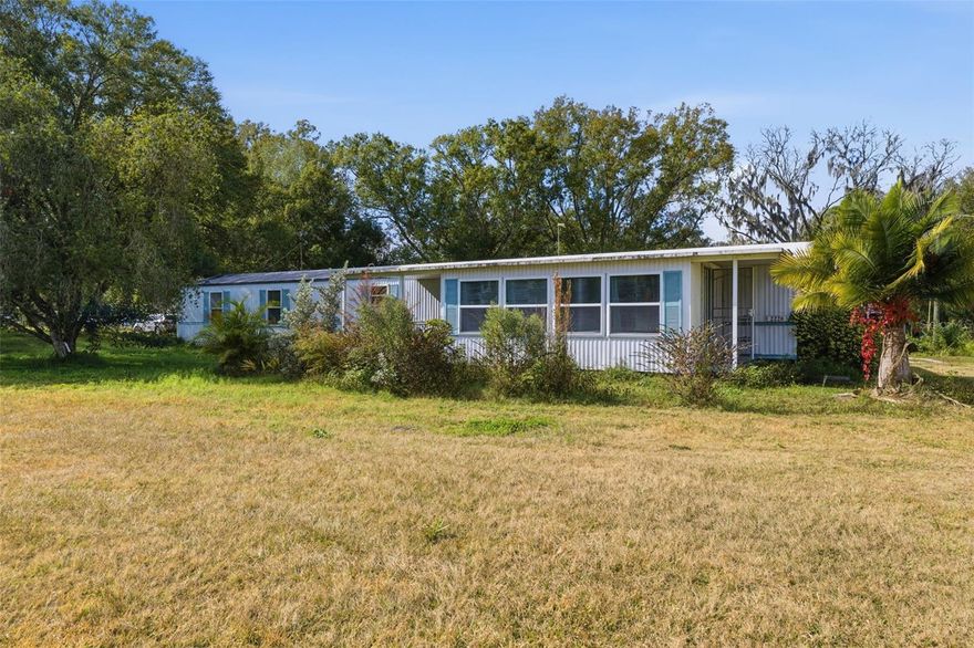 This 2 bedroom, 2 bathroom home sits on 1.41 acres with five additional buildings on the property, including a travel trailer with electric hookup and a 20x24 metal building. Inside the home, you will find an open floor plan with a large eat in kitchen and plenty of cabinet space. The bedrooms are located on opposite sides of the home for added privacy, and the primary bedroom has its own private bathroom. There are enclosed Florida rooms at both the front and back of the home, plus an extra bonus room in the rear.

Outside, the property is surrounded by mature trees that provide shade and peaceful outdoor spaces while still letting in plenty of sunshine. The outbuildings include a 20x24 metal building with 10 foot walls, a 12x12 open air shed with utilities, a 16x26 open air garage/workshop with utilities, a 10x12 shed, and a travel trailer with electric hookups.

This property is even better in person and has so much potential. With a little TLC, it could be the perfect place to call home and enjoy your own private retreat.