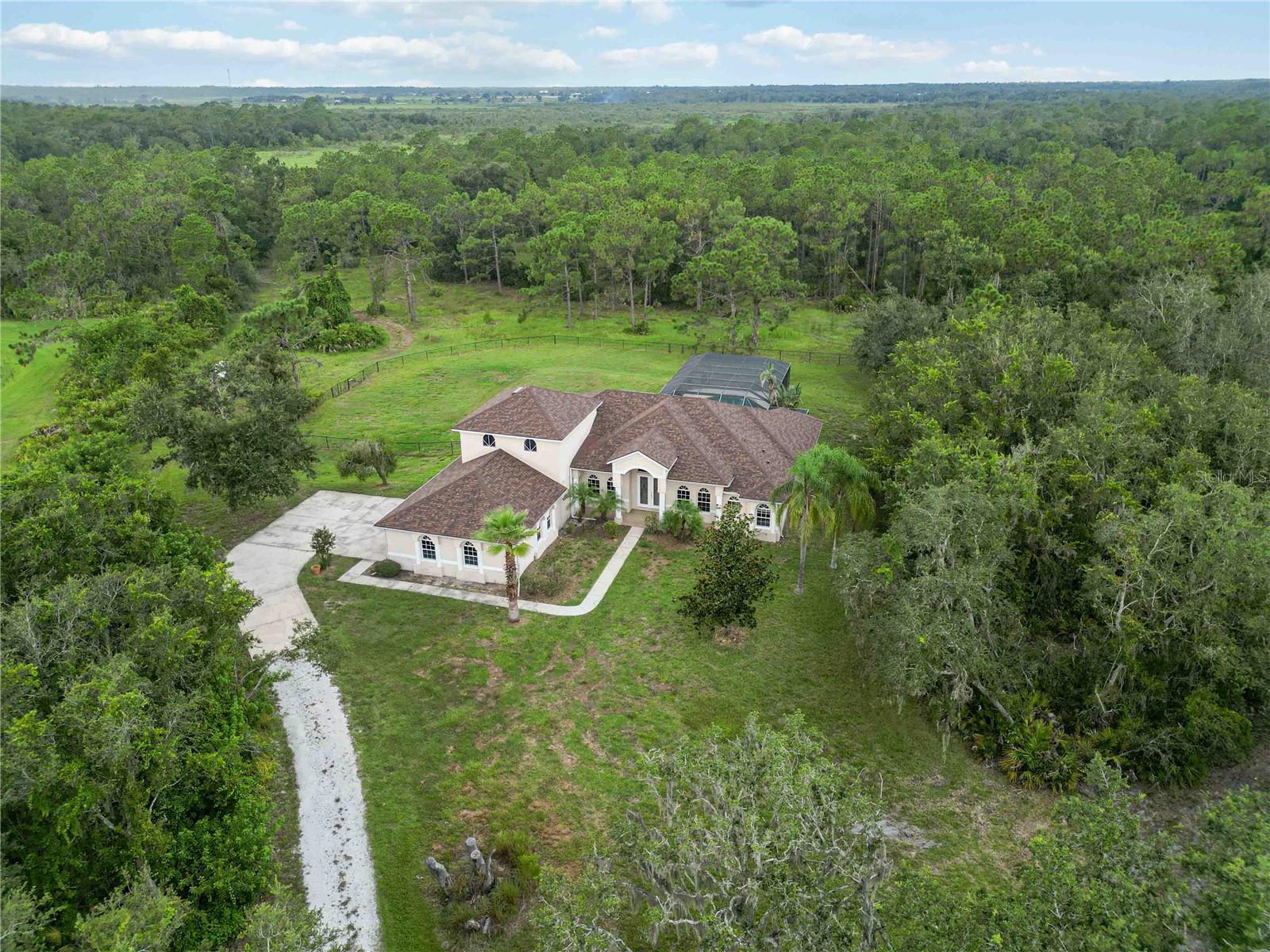 One or more photo(s) has been virtually staged. Ten acres—let that sink in. Not five, not two, but TEN private, build-ready acres wrapped around a 3,300-sq-ft retreat where every sunrise feels exclusive. At this price, land like this almost never pairs with a screened, heated pool, a three-car garage, a brand-new 2024 roof, a 2025 upstairs A/C, and solid 2004 block construction—yet here they coexist in effortless harmony.
Step through the etched-glass entry and the home opens like a deep breath: graceful columns, soaring ceilings, and a sweep of tile that draws you toward the kitchen—an open, social heart where friends linger at the island while dinner simmers. Slide the doors back and your backyard becomes a personal resort: turquoise water glistening under a panoramic cage, spa bubbling, birdsong echoing from the pines beyond the fence line.
Inside, an upstairs loft flexes into a media lounge, creative studio, or bunk room. Three secondary bedrooms sit in their own wing, while the massive primary suite is a sanctuary: tray ceiling, private pool access, and space for a reading sofa or Peloton. Storage abounds—oversize closets, walk-in pantry, and a three-car garage ready for toys, tools, and tack.
But the real magic lies outside. Imagine a barn with stalls, a second residence for extended family, a detached workshop, or simply acres of untouched Florida beauty—space to ride, roam, or re-wild. Zoned for horses, fully fenced, and minutes from conveniences, this property trades HOA rules for pure possibility. Come see where freedom, privacy, and value intersect, and claim the blank canvas you’ve been waiting for.