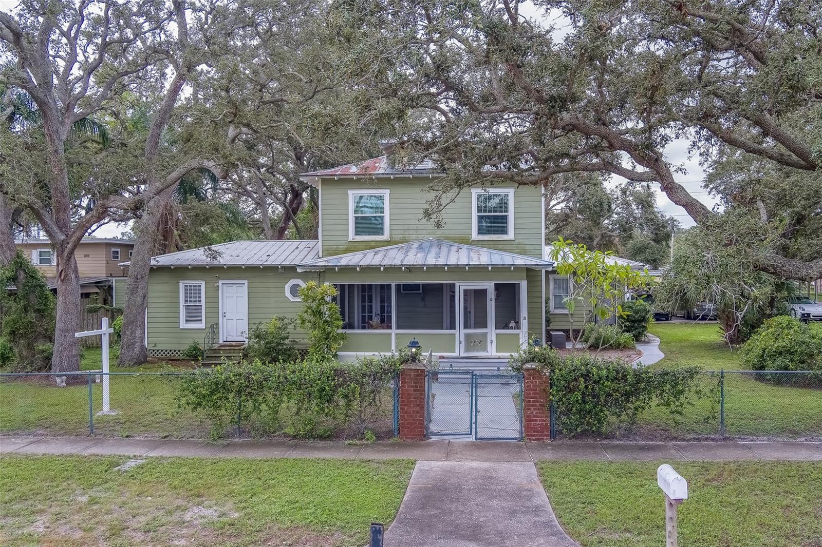 Step back in time with this rare gem in the heart of Largo! Built in 1926 and lovingly owned by the same family since the 1930s, 107 7th Ave SE offers a unique blend of timeless character and modern livability. Nestled along charming brick-lined streets, this enchanting property greets you with tree-filled grounds and an abundance of outdoor spaces for gathering, gardening, or simply unwinding beneath the Florida sky. The main home exudes warmth and history with 4 bedrooms, 3 bathrooms, a welcoming living room with a gas fireplace, formal dining room, laundry room, and a well-appointed kitchen. Upstairs, a rooftop terrace invites sunset views, while the large deck is perfect for entertaining. Adding to its charm and versatility, the estate includes an attached apartment, and a detached cottage—each offering 1 bedroom, 1 bathroom, a kitchen, and a living room. A detached 2-car garage, storage shed, and 12 total parking spaces (including 4 covered carports) make this historic retreat both practical and inviting. Best of all, the property sits in Flood Zone X—no flood insurance required. Just minutes from shopping, groceries, and the sparkling waters of the Gulf, this property is a true legacy home waiting to welcome its next steward. Make an appointment today!