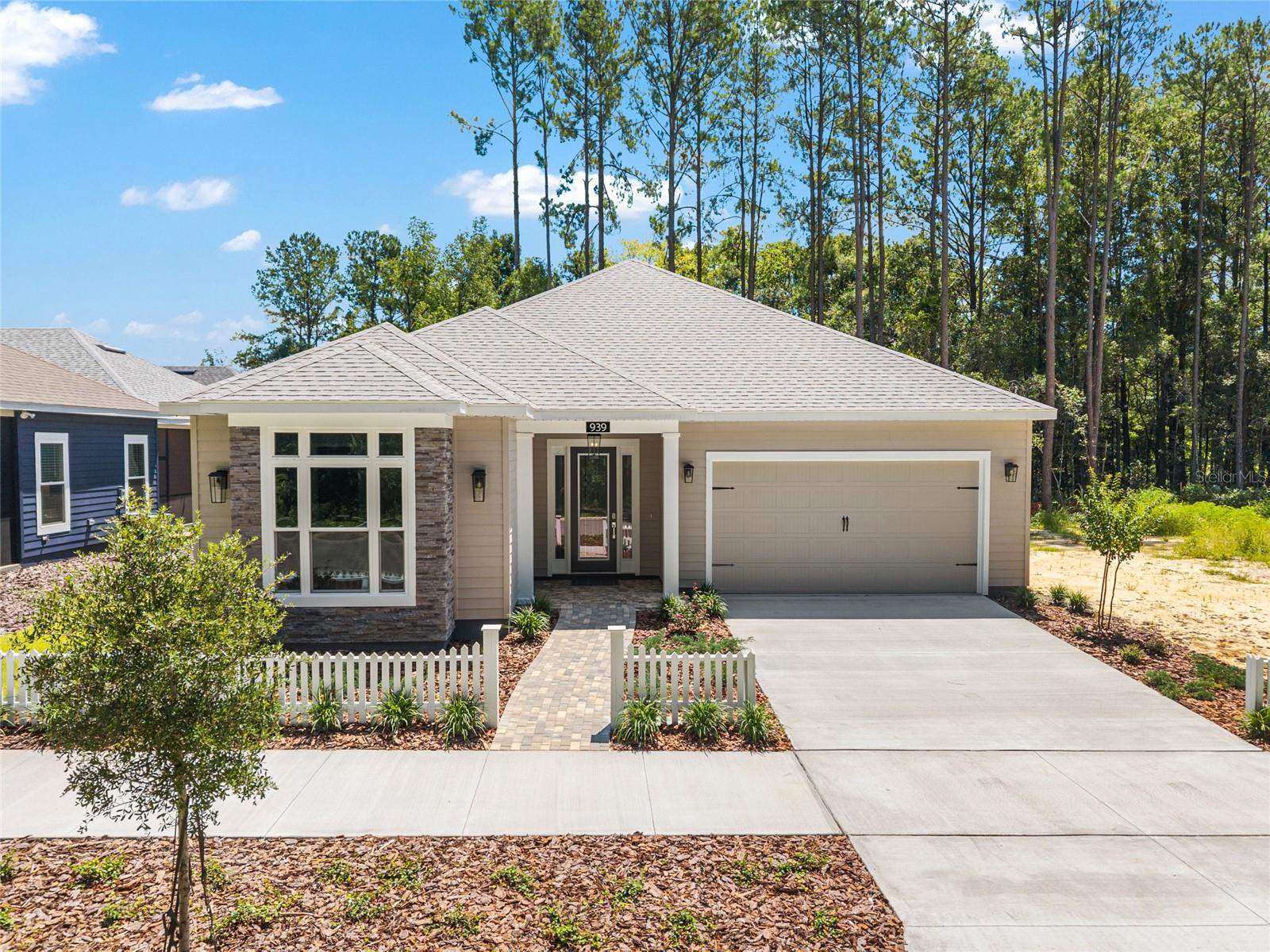 AVAILABLE NOW! NO CDD. Move-in ready NEW construction with a 1% builder credit toward closing costs. Welcome to the Sensi Model by renowned local builder Kara Bolton. This stunning 3-bedroom, 2-bath home with a bonus flex space and spacious 2-car garage is designed to combine style, comfort, and convenience for today’s homeowner. Step inside to find a bright, open floor plan with soaring 10-foot ceilings and elegant 8-foot doors, all enhanced by luxury wood-look plank flooring throughout. The gourmet kitchen is a chef’s dream, featuring quartz countertops, an undermount sink, solid wood cabinets with soft-close drawers, premium stainless-steel appliances—including an induction range, vented microwave hood, dishwasher, refrigerator, and disposal—and an exceptionally large pantry. Perfect for entertaining, the living room opens seamlessly to a covered and fully screened porch/lanai through glass doors, creating a welcoming indoor-outdoor space. The luxury primary suite provides a true retreat with a spacious walk-in closet and an en-suite bathroom featuring a walk-in shower, a quartz-topped double vanity, and a private water closet. The two additional bedrooms are spacious and comfortable, with a shared second bath that includes a tiled shower/bath and a quartz-topped vanity. Modern move in ready upgrades include a washer and dryer, window blinds for added privacy, endless hot water from a tankless gas hot water heater, a smart deadbolt, and coach lights on a photocell. Outside, the home’s exterior showcases durable Hardie board siding, decorative pavers, and a fully landscaped yard with eco-friendly Zoysia sod and irrigation. A screen-enclosed lanai completes this picture of tranquility. The low HOA fee of only $110 a month includes high-speed COX internet, a community pool, tennis and pickleball courts, a clubhouse, and partial front yard maintenance. Located just minutes from shopping and dining, this property is 4.5 miles from North Florida Regional Hospital, 11 miles from Shands and VA Hospitals, and 8 miles from the University of Florida. Buyer to verify all school zones with ACSB. Don’t miss the opportunity to own this exceptional home. Contact us today to make it yours!