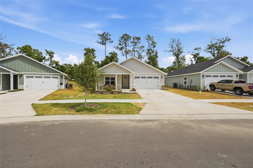 A quiet, winding street leads up to this like-new three bedroom 2 1/2 bath home with a hardiboard exterior, stacked stone accents and a welcoming front porch. The entry foyer allows space for a console table and leads to two bedrooms that share the hall bath. The house has ceramic tile flooring throughout, tasteful window coverings, 9 foot ceilings and crown molding, for a touch of elegance. The open kitchen overlooks the family room, encouraging casual, carefree living. Light cabinets and quartz counter tops, as well as high-gloss subway tile, add to the brightness of the kitchen. Appliances include a Whirlpool five-burner gas cooktop, a Whirlpool wall-mounted oven and microwave, a Frigidaire dishwasher and an LG stainless steel side-by-side refrigerator-freezer, with a water and ice dispenser. A walk-in pantry provides additional storage space, while a breakfast bar, with overhead pendant lighting, allows four to enjoy quick snacks—-or help with slicing, dicing and food preparation. The family room has a tray ceiling, space for a large dining table, ample seating to gather around a television screen and sliding glass doors that open onto a long covered porch, with paddle fans and views of the fully fenced yard. The principal bedroom has French doors leading to the outside porch and can accommodate a king-size bed, nightstands, a dresser and chest, as well as a lounge chair. It opens into a spacious bathroom, with bright tile floors, a large stall shower, with dual showerheads, a vanity with double sinks and wood cabinets, and an expansive u-shaped walk-in closet. A powder room is conveniently located off the wide entry hall, as is the laundry room. There is a like-new LG washer and dryer, shelving and a bench with hanging hooks to conveniently drop coats and backpacks when coming in from the two-car garage. Grand Oaks at Tower has a community clubhouse, swimming pool and kid’s playground. It is adjacent to a neighborhood shopping center and a short drive to the University of Florida campus, the UF Medical Center, North Florida Regional Medical Center, the Oaks Mall and I-75.