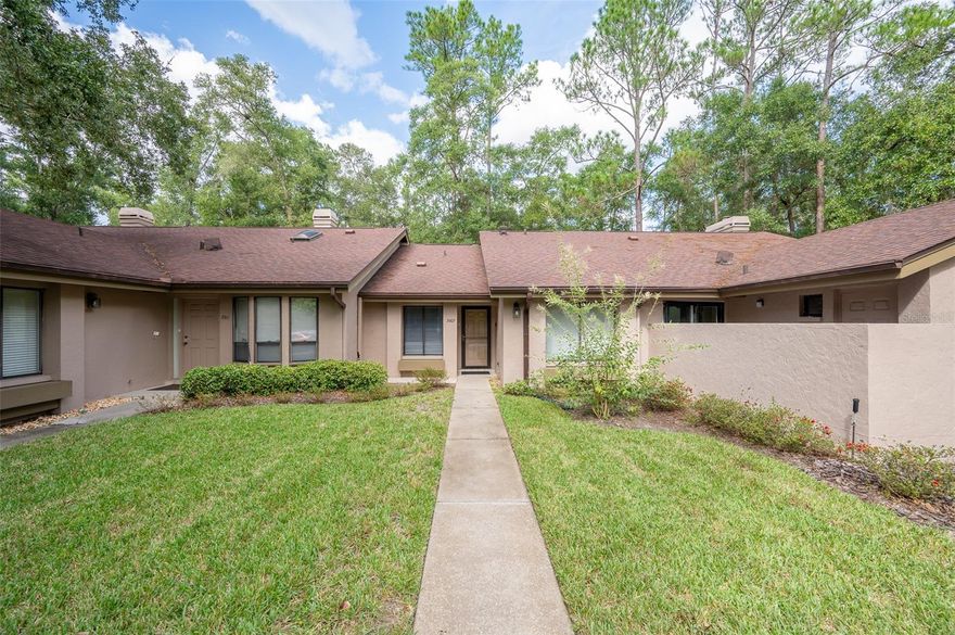 This spacious well-maintained, move-in ready, two-bedroom, two-bath townhome flat offers maintenance-free living at its finest. The bright, open floor plan features vaulted ceilings, creating an airy and inviting atmosphere. The kitchen has plenty of cabinet space, a pantry, an eat-in area, and a breakfast bar that opens to the dining room and great room. The great room is highlighted by a triple sliding glass door that leads to a screened porch with serene views of a private pond and fountain.The primary suite includes an en suite bath, a double slider glass door, a generous walk-in closet, a large vanity, and a walk-in shower. The sizable secondary bedroom has easy access to a hall bath with a tub/shower combination. Engineered wood and tile flooring throughout—no carpet. Additional conveniences include an inside laundry closet, a storage room off the screened porch, two assigned parking spaces, and guest parking. Wood Creek Village is a private community with its own pool and cabana. It is NOT a condominium association making it easier for financing. Ideally located in the heart of Gainesville, this home is just minutes from Fresh Market, Publix, popular restaurants, and shopping.