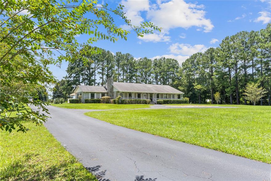 Beyond a stately, custom-designed gated entrance, a tree lined drive leads you into a property that feels like its own private world. Here, on 5.5 acres of high, dry pasture just outside the charming town of Williston, sits an immaculately maintained home built with the coveted strength and beauty of Ocala block. This is more than a house—it’s a sanctuary where every detail has been thoughtfully crafted.
From the moment you step through the front door, you’re welcomed by soaring ceilings and a light-filled open living space, anchored by a massive gas-fueled stone fireplace—a striking centerpiece that’s as inviting on cool evenings as it is stunning year-round. Framed by floor-to-ceiling windows that bring the outdoors in. Plantation shutters throughout offer both elegance and privacy. The kitchen is a culinary dream—equipped with a gas range, wall-mounted oven, double sinks, expansive counters, a large island with a breakfast bar that invites slow mornings with coffee or lively gatherings with friends.
The primary suite is a retreat unto itself—massive in scale, yet intimate in feeling—with direct access to the back porch and pool. The en suite bath offers a spa-like escape, featuring a large walk-in shower and a separate soaker tub perfect for long, quiet evenings.
Step outside and the resort-like amenities unfold: an 8-foot-deep saltwater pool glistens in the Florida sun, paired with a heated spa for year-round enjoyment. A large covered back porch provides the perfect setting for entertaining, while a convenient pool bath makes hosting effortless.
The land is as impressive as the home—fully fenced and cross-fenced, with well-maintained pasture ideal for horses. The property’s elevated position keeps it high and dry, and a whole-house generator with years’ worth of fuel storage offers unmatched peace of mind.
Despite its private, rural feel, the location couldn’t be more ideal: just 19 miles to Gainesville, 23 miles to Ocala, and 45 miles to Cedar Key and the Gulf of Mexico. Here, you’ll find a rare blend of seclusion and convenience.
Pass through the gates, and you’ll understand—this is more than property. It’s a legacy, ready for its next chapter.