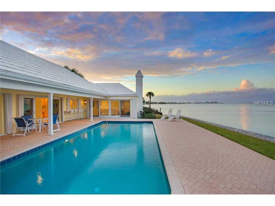 This casually elegant Bermudian residence is enviably positioned on one of the most easterly points of the Longboat Key shoreline, affording smashing Bay and City skyline views. With 273' of shoreline, the home is wonderfully bright and open to the beautiful waters surrounding it. Deep water dockage is a given on the canal side of the property leaving the over 131' of bay front open for nothing but views of the water, the birds and the dramatic sky. The entry foyer welcomes guests with a big bay view.  The large living room offers two sides of windows and opens out to the terraces, pool & bay. The wood-burning fireplace with slate hearth and carved mantle is a focal point of this room. Lovely millwork and built-in bookcases and storage add to the feeling of luxury. A large dining room opens to the bay with windows on the East, affording wonderful views. The handsome kitchen is equipped with the finest in equipment and cabinetry. The view from the kitchen sink is a show-stopper and opens to a serving bar for the patio & pool area. The separate Master Suite is large and features a fireplace, windows opening to the bay and the pool and his & her baths and closets. The two guest suites enjoy privacy from the Master. A wonderful library/office/family room is the epitome of inviting comfort and features water views & built-in book cases. The attached garage is side entry, complimenting the appealing streetside presence of the home. The .43 acre lot gives privacy and exclusivity with its' cul de sac location.