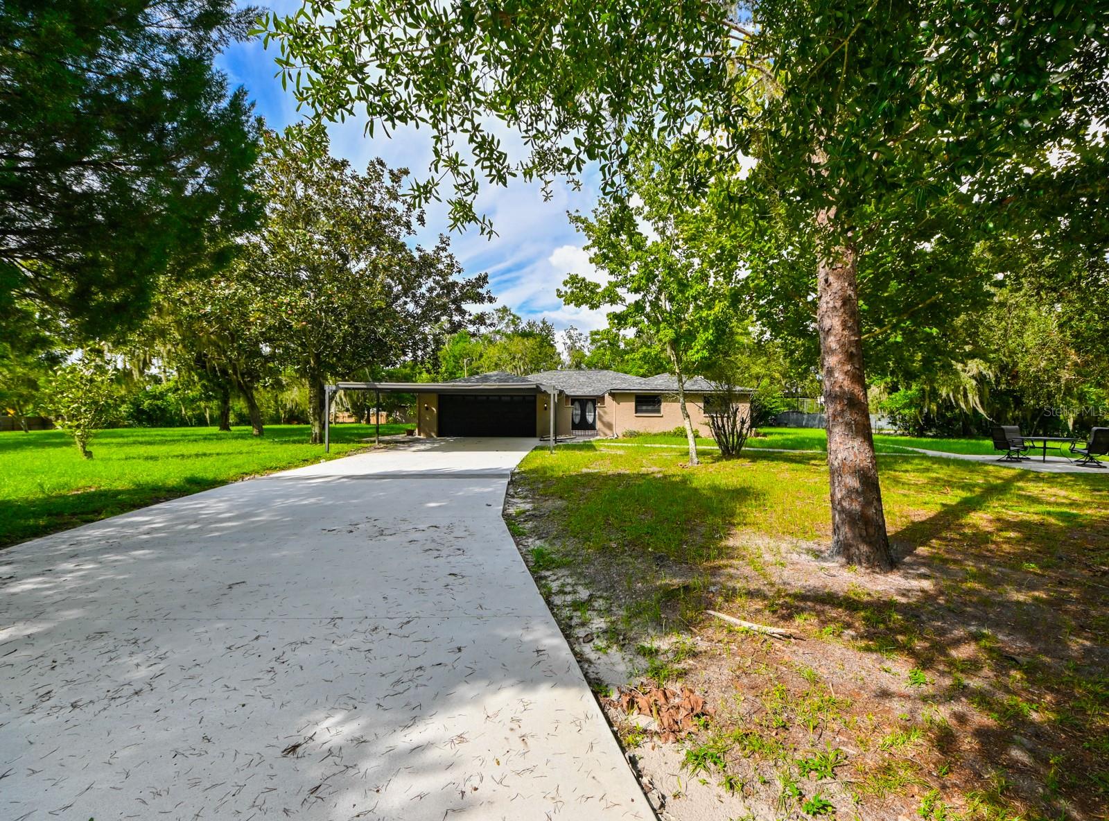 Welcome to this stunning beautifully upgraded home offering 4 bedrooms, 2 modern bathrooms, a huge open kitchen and living room all Nestled on a private 1.3-acre lot with a park-like setting, the property features a 2-car garage, separate RV high carport, large shed, and mature shade trees providing natural beauty and tranquility. Step inside through double front doors into an open-concept living space, where new porcelain tile flows throughout. The fully renovated kitchen is the heart of the home, boasting Level 3 quartz countertops, a huge center island with glass pendant lighting, under-cabinet lights, stainless steel appliances, and new wood cabinets. The living room—perfect for entertaining, hobbies, or relaxing—with matching window blinds for privacy. From here, access a large screened-in porch or unwind in the second screened area with a hot tub. The master suite includes a sleek new shower with glass frameless doors and modern tile. The second bathroom also features beautiful floor-to-ceiling 4-ft tile, LED lighting, and a new bath fan. Upgrades galore: fresh paint, new ceiling fans, outlets, LED lighting, closet doors, baseboards, epoxy garage flooring, brand new roof and driveway (with permit), new electric panel, newer 5-ton A/C, and a brand new water heater (2025). Outdoors, enjoy space for a fire pit, basketball, pickleball, tennis, or skateboarding on a fenced-in concrete area with multiple yard access points. Utilities are low thanks to a well and septic system—an added bonus in today’s market. This move-in-ready gem is the complete package—privacy, space, and top-to-bottom upgrades with no HOA restrictions!