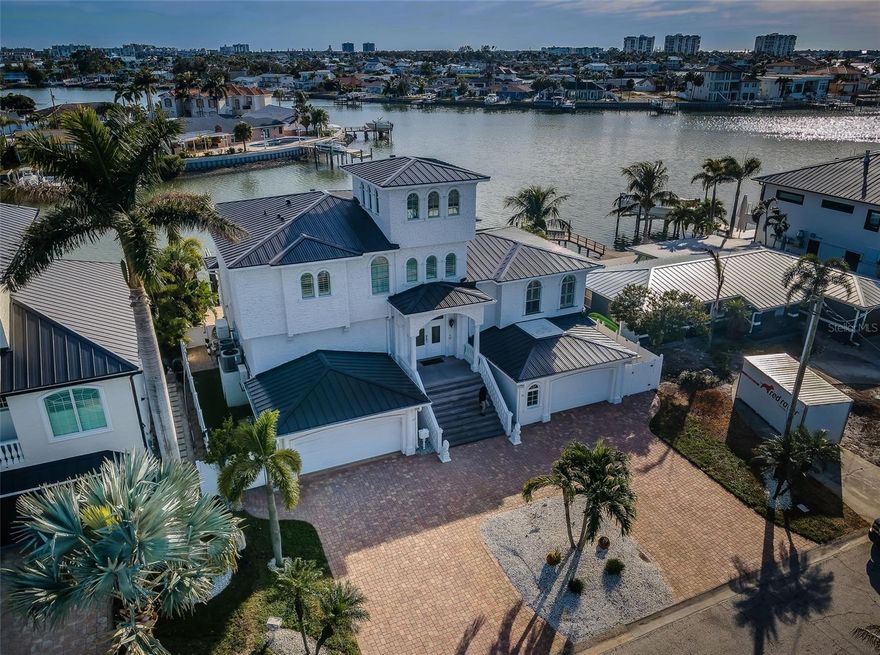 CLOSE TO THE BEACHES, THIS SPACIOUS AND BEAUTIFULLY UPDATED WATERFRONT RESIDENCE OFFERS RAPID ACCESS TO THE GULF. Boasting elegant high-quality finishes inside and out, you’ll love the attention to detail of this impressive home. A fine double door entry
opens to an exceptional multi-function great room plan with stately columns and lovely water views. The exciting and sumptuous Euro-style kitchen enjoys a massive quartz island bar, porcelain farmhouse sink, Subzero/Wolf/Bosch SS appliances, gas cooking, rich contemporary cabinetry and resplendent tilework, all complemented by radiant under-cabinet lighting. You’ll appreciate the full-size laundry area with storage, as well as the extensive storage areas accessible from within the garage. Step up to a half level that supports two bedrooms (one facing the water) and a superb full bath with glass shower enclosure and striking minimalistic dual vanities. The owner’s suite level provides a huge primary bedroom (water-facing), private access to a terrific, covered waterfront balcony, and a gorgeous custom walk-in closet system with an inspiring array of specialty pull-outs. The owner’s bath enjoys additional closet storage, exquisite dual quartz vanities, a
Jacuzzi jetted spa tub and a large designer-tile multi-head walk-in shower system. The 4th bedroom (or office/den), with private luxury full bath, includes stairway access to a 17ft-deep 190sqft observation room with commanding 270-degree views of the waterways; observation room is ideal as a mini art studio or reading room. A 375sqft multi-purpose lower-level game/fitness area opens to a dazzling 460sqft
covered lower-level entertainment deck with a wonderful SS outdoor gas cooking center, wide bar area, and generous dining/lounging space. The sizable pavered deck encases a substantial Pebbletek Pool and spa (installed in 2020), and the deck transitions to an updated seawall and composite dock with seating bench, shower, and large-capacity lift with excellent boating water. New metal roof (2025), Generac gas generator, hurricane impact windows and doors, and many, many extras. An outstanding value in a highly desirable location. Dimensions are estimates, buyer to verify.