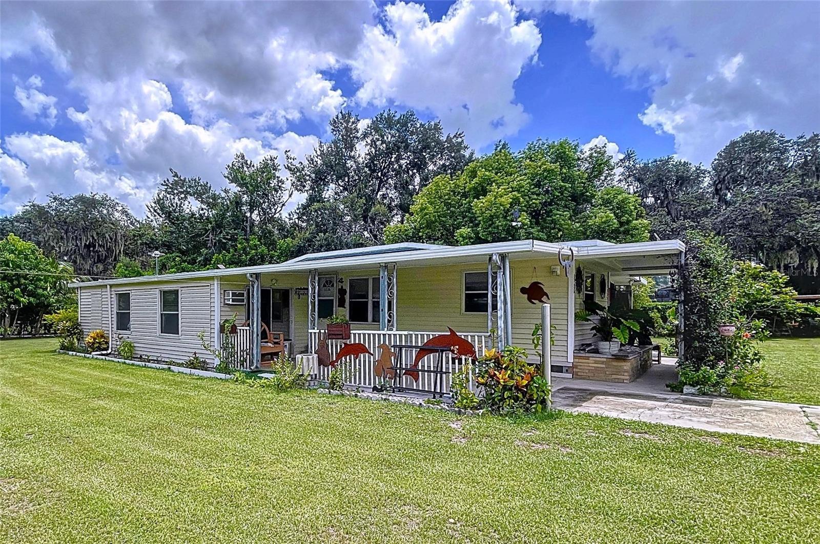 This 2-bedroom, 1.5-bath mobile home sits on an almost half-acre private lot in the quiet, semi-rural charm of Auburndale. It's a great way to enjoy the Florida lifestyle without having to deal with an HOA. It was built in 1971 and sits on 0.42 acre fully fenced and surrounded with lush fruit trees and vegetation. It's a great fit for someone who wants to save money and have some additional space to breathe. The split-bedroom layout inside is useful since it provides each room a little more privacy. The kitchen opens up to the dining room, making it simple to serve after you cook. The living room has an additional bedroom attached and an enclosed porch. The family room is oversized, making it easy to fit family and friends while hosting. The laundry room is separate from the rest of the house, so duties don't become in the way. The screened porch is a wonderful place to drink your morning coffee and get some fresh air. There is also a built-in bar in the backyard! The carport beneath the roof keeps your car cool all year long. Tools, hobbies, or gardening gear can all fit in a storage shed. The spacious lot outside gives you endless options. You may grow a garden, build a workshop, or just enjoy having more space than most subdivisions do—there is NO HOA. The location is great because it's peaceful but only a few minutes from I-4, making it easy to get to Tampa or Orlando. The community of Auburndale has a welcoming vibe because it is close to lakes, parks, and the historic downtown area in Auburndale and LEGOLAND. This property is ideal for first-time buyers, investors, or anyone who wants to downsize to a manageable, single-level home with a huge yard. The pricing is also hard to beat in Central Florida. ***Recent updates include a septic tank installed in 2019, a well pump installed in 2019, windows replaced between 2019 and 2025, fencing.