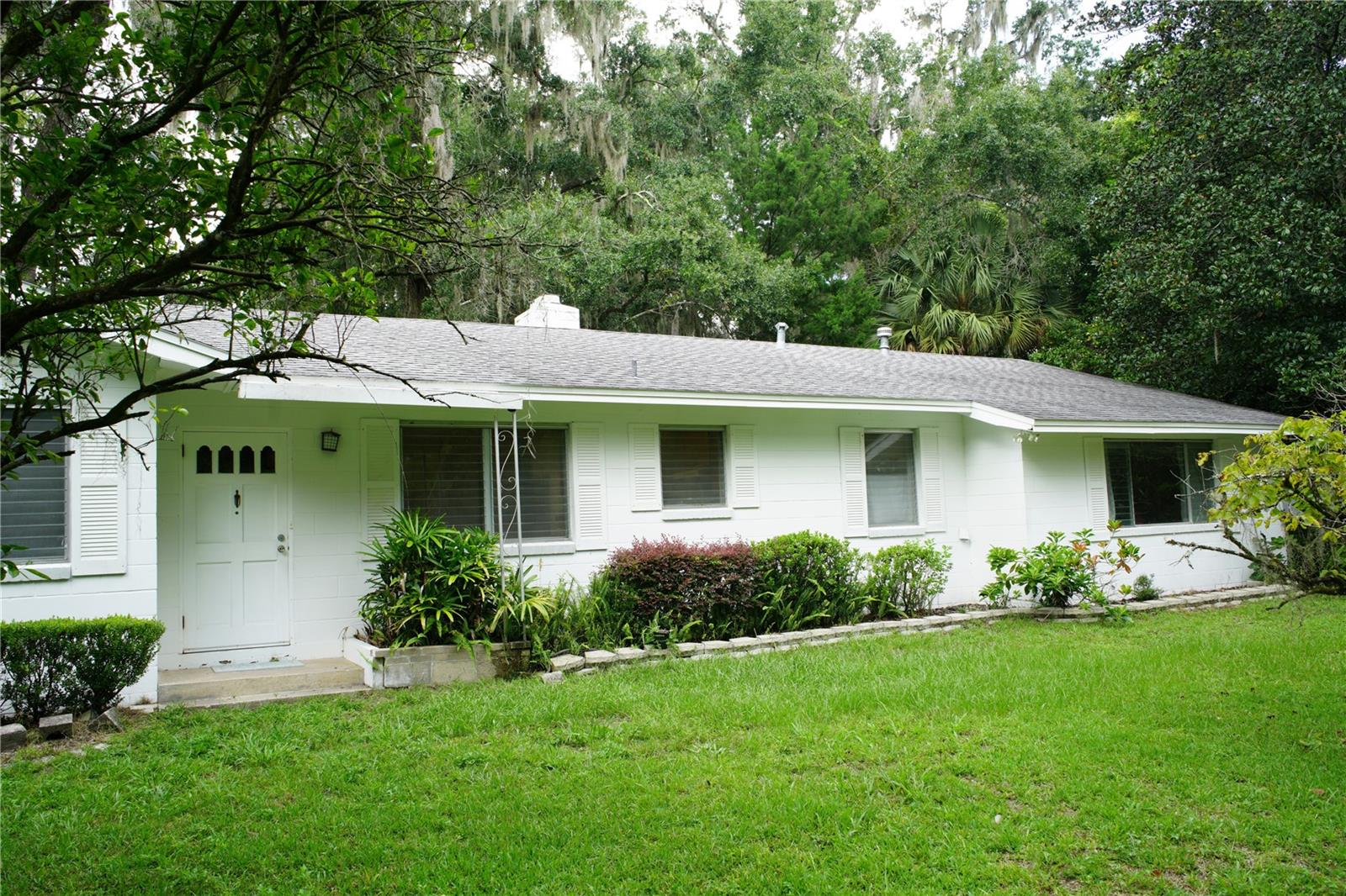 Investor Alert! Amazing opportunity to update this beautiful 1957 Mid-Century Modern home on a .84-acre wooded lot. Walls of glass bring the outside inside with a view of hardwood trees and lush old Florida growth. Enjoy the extensive patio across the back of the house for your barbecues and Gator Gatherings. You will love the secluded setting nestled by hedges at the back of the neighborhood, providing the privacy you crave. The living room boasts a vaulted ceiling with wood beams, built-in cabinets, and a stone, 2-sided wood-burning fireplace viewed from the dining room as well. There are storage areas throughout the house in various nooks and crannies. The spacious kitchen was updated with wood cabinetry and includes a breakfast nook with built-in benches. This one-owner home was expanded to provide an in-law suite with a private bath and screen porch. Check out the old concrete block shed/workshop at the back of the property, waiting for your personal touch. The roof was replaced in 2020, the HVAC system was replaced in 2017, the septic tank and drainfield were replaced in 2017, and the home was replumbed with PEX in 2017. Embrace the vintage charm and modernize the rest with your personal vision. CASH ONLY! and As-Is Sale, please.