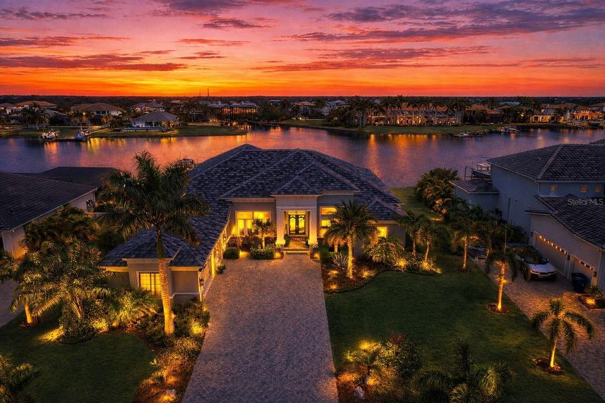 Exquisite waterfront home in Bay Estates Preserve at MiraBay offers resort-inspired coastal living at its finest. Set along a tranquil lagoon with direct access to Tampa Bay and the Gulf, this customized waterfront residence blends architectural precision and coastal design. Completed in 2022 and positioned on a .41-acre homesite with 100 feet of waterfront views, the home was designed to capture panoramic water vistas while offering the comfort of a single-story layout spanning 4,640 sq ft. A paver driveway, landscape lighting, cedar accents, and hurricane-impact glass entry doors introduce a residence where craftsmanship is immediately evident. Inside, fifteen-foot ceilings, crown molding, custom millwork, and oversized porcelain tile create open, elegant interior. WHOLE-HOUSE HURRICANE-IMPACT WINDOWS and expansive pocketing sliders blur the line between indoor and outdoor living, filling the home with natural light and water views. The main gathering areas flow seamlessly between the living room, dining space, and family room, where architectural details, designer lighting, and fireplaces create both sophisticated and welcoming spaces. A built-in bar with illuminated glass cabinetry enhances the home’s entertaining appeal. At the center of the home, the chef’s kitchen features an impressive eleven-foot quartz island beneath handcrafted wood ceiling beams. Monogram professional appliances include a six-burner gas rangetop, double ovens, Advantium speed oven, and integrated refrigeration. Bespoke cabinetry with integrated lighting and designer backsplashes complete the space. The owner’s suite offers a private waterfront retreat with lagoon views and automated window treatments. Entered through custom wood-and-glass barn doors, the spa-inspired bath includes a freestanding soaking tub, rain and aromatherapy shower, floor-to-ceiling tile, quartz vanities, and backlit mirrors. A customized boutique-style wardrobe room with handcrafted cabinetry and a quartz-topped center island adds exceptional luxury. Outdoor living defines the home. Beneath a 1,250-square-foot covered lanai with wood ceilings, coastal breezes flow across a spectacular infinity-edge pool and champagne spa finished in glass tile and surrounded by leathered marble decking. Waterfalls cascade along a privacy wall while a natural gas fire feature reflects across the water, creating an atmosphere perfect for both quiet evenings and gatherings. A sun shelf, swim-up seating, color-changing lighting, and pool automation enhance the experience. Entertaining continues in the outdoor culinary pavilion featuring a natural gas grill, stainless Kamado grill, and custom Gaucho grill, complemented by stone countertops, refrigeration, an ice maker, and illuminated storage overlooking the canal. For boating enthusiasts, a maintenance-free Trex dock extends over protected waters with a remote-controlled 16,000-pound lift, shore power, and water service, accommodating vessels up to thirty-five feet with direct access to Tampa Bay and the Gulf. Modern systems include dual Trane HVAC with UV purification, a tankless gas water heater, R-49 insulation, smart irrigation, whole-home water softening, structured wiring, Wi-Fi expansion, advanced security, and a three-car garage with EV charging. Residents of MiraBay enjoy resort-style amenities including waterfront clubhouse dining, heated pools, fitness facilities, tennis and pickleball courts, and kayaking. Schedule your private tour today.