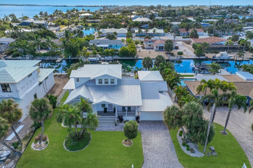 IMAGINE living on an Island in the warm tropical paradise of West Florida - This KEY ROYALE Canal Front Home is Located on Anna Maria Island and being sold turnkey furnished. A boaters dream with mechanical boat lift and direct access from the canal to the Intercostal waterway, Tampa Bay, and the Gulf of Mexico. For golfers, no need to drive to the mainland to get in a round. The only golf course on the island, the private Key Royale Golf Club - a nine-hole private course, is only a short walk or golf cart ride away.   This open concept Single Family Home has 4 bedrooms, 4.5 baths and approximately 2,651 square feet.  The home features tall ceilings, tall solid doors, designer kitchen, outdoor access pool bath and a spacious upstairs primary bedroom with balcony and high-end finishes.  Relax on the expansive patio which is ideal for large family/friend gatherings or just enjoy the serene space with a nice cold ice tea. Entertain in your covered outdoor space with built-in outdoor grill, matching polywood dining table, chairs and reclining lawn chairs with umbrella for outdoor comfort, -- and all this surrounding a crystal-clear swimming pool. The pool has a heater for the cool days and a chiller for those hot summer months.  Enjoy each day swimming, boating, fishing, kayaking, crabbing and grilling your catch for a fabulous fresh fish dinner.  Don’t miss out on this Florida lifestyle home. Just a short golf cart ride away are Anna Maria Island’s famous beaches and a variety of local dining and shopping opportunities. Enjoy sunsets and sunrises from your very own island home and you might even catch a manatee and dolphin swim by. This is island living at its finest! Please click the interactive 3D walk-through link.  Schedule a visit today.