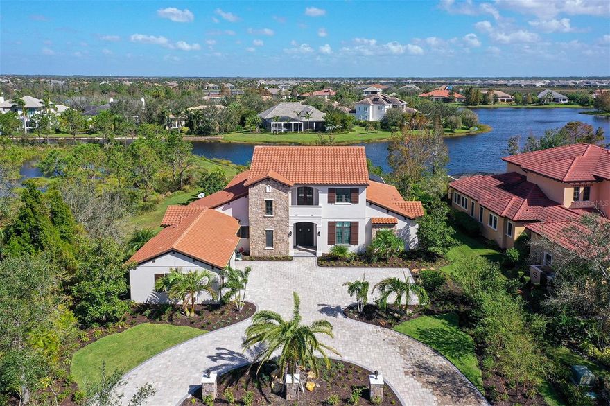 Set on a premium lakefront homesite in the Lake Club of Lakewood Ranch, this 5,000+ SF Green Certified estate seamlessly combines spacious elegance and practical luxury. Travertine floors, an open floor plan, and hurricane impact doors and windows offer sophistication and peace of mind, while the Viking-equipped kitchen and great room with a dry bar, wine fridge, and gas fireplace provide a refined space perfect for entertaining. This home features two bonus rooms. The first with disappearing sliders opening to the lanai where you can find a remodeled outdoor kitchen, heated saltwater pool and spa, and beautiful lake views. The second one is on the upper level and features French doors to a quiet balcony. All bedrooms in the home are en suite, closets are custom-organized, and the main-floor guest suite even includes French doors to a private patio. In addition to the recently expanded circular driveway and all new landscaping, special features include a private office (currently used as a theater,) a hidden kitchen pantry, tankless hot water heater, crown molding throughout and much more. Within the Lake Club’s gated community, residents are treated to a wealth of amenities including a grand clubhouse, resort-style pools, fitness center, tennis courts, walking trails, and a calendar full of social activities, creating a lifestyle that is as luxurious as it is vibrant. In this exquisite residence, you'll discover the epitome of Florida living, where elegance and comfort merge seamlessly with the allure of The Lake Club's resort-style amenities. Lakewood Ranch is the best-selling multi-generational community in the USA near world-class dining, shopping, beaches, and A+ schools.