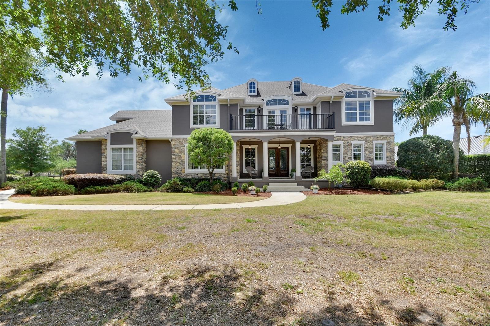 EXECUTIVE-STYLE home offers SPACE, PRIVACY, and high-end features, located in a GATED community and just over 1 ACRE. A three-car GARAGE, screen-enclosed, in-ground POOL with spa, and thoughtful updates throughout make this property move-in ready. The home has been extensively updated, including a refreshed exterior and interior color palette, major first-floor remodeling, and new wood flooring. The layout is ideal for both family living and entertaining. An impressive covered front entry opens to a grand foyer with seating and space for a piano. The remodeled dining room features a striking chandelier and comfortably accommodates larger gatherings. The kitchen has been fully redesigned to improve flow and functionality, with new cabinetry (including glass-front uppers), a work island with sink, walk-in pantry, coffee bar, and stainless appliances. The 15x11 breakfast room offers ample space and overlooks the rear yard and pool.
The living room features a 21-foot ceiling, custom built-in wall unit, gas fireplace, and expansive views of the lanai. The first-floor primary suite includes lanai access, a triple tray ceiling with crown molding, and a large en suite bath with walk-in shower, jetted tub, dressing area with sink, private water closet, and oversized closet. Half bath for guests is located on the first floor. A beautiful curved staircase leads upstairs, to a spacious landing, four guest bedrooms, and an additional family room. Three bedrooms include en suite baths, and two bedrooms offer access to a refreshed balcony. The upper family room works as a craft room, office or movie room. The main floor utility room has been updated and leads directly to the garage.
The screen-enclosed salt water pool area includes swim-outs, spa, and ample seating, making it a great space for entertaining or relaxing. Peace of mind with a Termite Bond and NEW ROOF 2020. Conveniently located just minutes from downtown DeLand, Stetson University, hospitals, medical facilities, and I-4, with easy access to beaches, Orlando, and area attractions. Three major airports are about an hour away. Welcome to the Florida Lifestyle you deserve!
