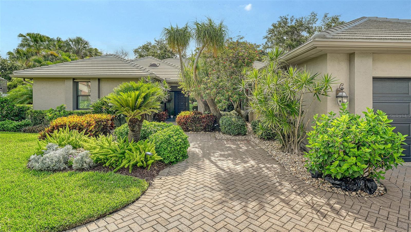 Located in Sarasota’s coveted and 24-hour guard-gated West of Trail community, The Landings, this beautifully reimagined 3-bedroom, 3-bath residence with a bonus room offers refined coastal living and peace of mind through extensive, high-quality updates. Situated on a lushly landscaped lot with mature trees and privacy and not in a flood zone, this 2,921 sf home blends timeless architecture with thoughtful modern improvements, all just minutes from Siesta Key’s world-famous beaches and Downtown Sarasota. Hurricane-impact windows were added in 2023, and the newer roof and updated PVC plumbing offer structural integrity and long-term value. Design upgrades include porcelain tile flooring and beautiful custom wood cabinetry and built-ins. The fully updated kitchen features premium stainless appliances, Silestone counters, stylish cabinetry, a picture frame window overlooking the beautiful garden, a convenient pass thru window to the lanai, and custom walk-in pantry. The adjacent dining room is perfect for entertaining and the formal living room with its high ceiling is anchored by a woodburning fireplace with tiled hearth and built-ins. The split-bedroom floor plan offers privacy and functionality, with all 3 bedrooms, (one currently outfitted as a convenient home office with solid wood built-ins) boasting custom walk-in closets and lovely bathrooms. A spacious bonus room is light and bright and includes a redesigned alcove with floor-to-ceiling custom built-ins to house books, media, or art. Every inch of this home reflects quality, style, and enduring craftsmanship. The interior of the home flows seamlessly to the elegant and serene exterior where you will enjoy the professionally redesigned landscape with exquisite plantings, brick paver driveway, meandering walking path, elevated relaxation area, peaceful fountain, and custom exterior lighting. The spectacular pool area underwent a major renovation in 2020 which included resurfacing with Pebble Tec (lifetime warranty), installation of a new heater and pump, and the addition of a stylish new Italian tile surround. The lanai was rescreened in 2023 and the deck was upgraded with a high-performance Pro Tech surface for durability and beauty. Located behind the gates of The Landings, residents enjoy tree-canopied streets, a nature trail leading to Roberts Bay, and optional membership to the Landings Racquet Club, offering tennis, pickleball, a heated pool, fitness center, and clubhouse. With proximity to A-rated schools, Southside Village, Sarasota Memorial Hospital, and the cultural amenities of downtown Sarasota, this property is a rare opportunity to own a truly move-in-ready home in one of Sarasota’s most sought-after communities.