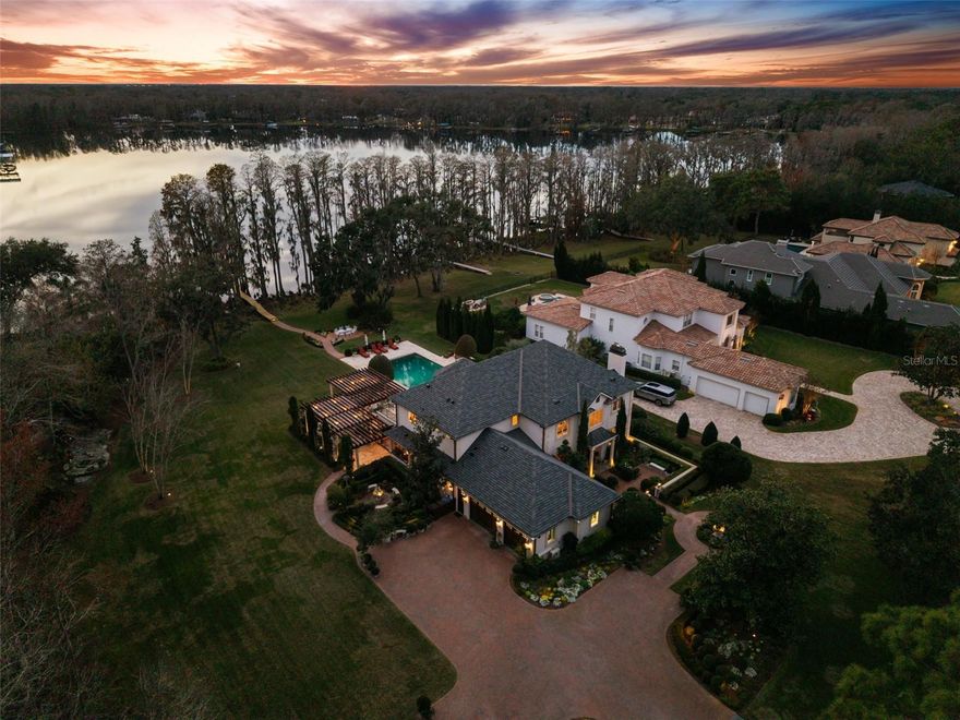 Introducing 5902 Fitzgerald Road - A French garden estate where timeless European architecture, curated landscapes, and lakeside living converge along the shores of Rock Lake, offering approximately 100 feet of direct lake frontage. Set within a gated enclave on 7.12 acres, the property delivers extraordinary privacy and long term preservation with no concern of future nearby development. The 5,000 square foot residence features four bedrooms and four and a half baths, with all bedrooms thoughtfully positioned on the second level, including the primary suite. The main level balances function and elegance, offering a media or bonus room, a dedicated office or study, and formal living and dining spaces that flow seamlessly into the kitchen. The air conditioned 987 square foot three car garage has been intelligently designed to serve dual purposes, featuring a built in gym that extends for workouts and retracts to accommodate full garage use. Additional highlights include custom built in cabinetry, integrated lighting, surround sound, and imported mahogany garage doors that provide exceptional insulation while delivering a refined, luxury aesthetic. From the moment you enter, uninterrupted lake views draw you through the living spaces and into the heart of the home. The chef’s kitchen is a statement of craftsmanship and performance, anchored by the main island with custom beaded inset cabinetry, granite countertops, a custom stone hood, Viking professional range, dual Sub Zero refrigerators, and two Miele dishwashers. A sunlit breakfast area opens directly to the terraces and pool, creating a seamless indoor outdoor flow ideal for both daily living and entertaining. Throughout the home, architectural details elevate every space solid red oak flooring, raised panel millwork, substantial crown molding, solid interior doors, European chandeliers and sconces, and an electric chandelier lift in the foyer. Modern luxury is delivered through Savant and Vantage whole home automation, programmable lighting, multi zone audio and video, hurricane rated Pella windows and doors, a Vivint security system, and a 30KW whole house generator. The grounds are a defining feature of the estate. Sculpted hedges, formal topiaries, travertine terraces, and European inspired stonework form a sequence of garden rooms reminiscent of the French countryside or the Italian lakes. The resort style pool and spa, approximately 44,000 gallons, are framed by a travertine deck, gas fireplace, and a custom cypress pergola with retractable canopies and integrated lighting. An extensive FX Luminaire landscape lighting system with over 120 fixtures transforms the property after dusk. A private path leads to the lakefront dock, featuring new decking, a boat lift, and a separate jet ski lift perfect for boating, paddleboarding, and sunset evenings on Rock Lake. Recent improvements include a brand new roof, fresh interior and exterior paint, refurbished pool and spa equipment, updated outdoor kitchen appliances, new dock planks, upgraded exterior fans, and refreshed landscaping ensuring peace of mind for the next owner. Offered for the first time, 5902 Fitzgerald Road is a rare European inspired lakefront estate where architecture, gardens, and everyday living feel effortlessly romantic, refined, and enduring.