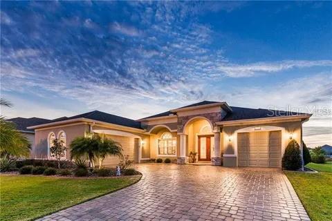 Beautifully designed, this 2,600 sq ft 3 bdrm/3 full bath home is situated on the water in the much sought after Lakes of Mt Dora a 55+ gated community.
Impeccable neighborhoods lead to the ranch style three car split garage home that is itself beautifully manicured. The entire house has tray ceilings and crown moldings. Immediately upon entering there is a semi-formal dining area followed by an open concept living room/kitchen. The kitchen is well equipped with stainless steel appliances, designer cabinets and granite countertops. Besides a huge main bedroom suite and two other bedrooms and baths there is also a good sized but still cozy room with a fireplace that could be used as a den/office/4th bedroom. Finally, there is a breakfast nook immediately off the kitchen with panoramic views of the water.
A full wall sliding glass door system opens up the living room into the enclosed lanai creating an incredible great room that you have to see to believe.
A community clubhouse with all the amenities and proximity to the historic city of Mt Dora round out the perfect home to entertain in or just sit back, relax and enjoy your day.
