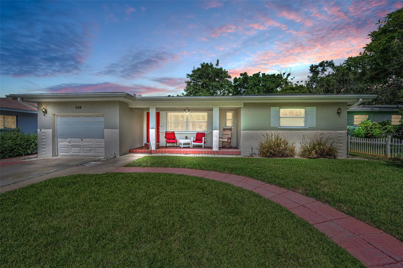 One or more photo(s) has been virtually staged. Welcome to your slice of paradise in the heart of Downtown Dunedin! This beautifully maintained 2-bedroom, 2-bathroom, 2,300 sqft home sits on an expansive ¼-acre lot just steps from the Pinellas Trail, TD Ballpark, vibrant local breweries, restaurants, and world-famous sunsets. Step beyond the lush, landscaped front yard to find a cozy, covered porch that’s perfect for enjoying your morning coffee. Inside, you’re welcomed by a spacious living room with original hardwood floors throughout and a large double-pane bay window that floods the space with natural light while offering serene views of the front yard. Continue into the the kitchen where its a delight for any home chef, featuring solid wood cabinets, Corian countertops, a new LG ThinQ stainless steel refrigerator, and a casual eat-in nook that overlooks the private backyard. A convenient pass-through door leads to an oversized one-car garage with soaring vaulted ceilings—ideal for storage, workshop, or a loft. Continue into the open Florida room, where newer windows and 10-foot ceilings invite in the bright Florida sunshine, offering flexible living space with panoramic views of the lush, fully fenced backyard designed for entertaining. Enjoy a large paved patio area, plenty of grassy areas for play, and room to add a pool. After a day of exploring downtown on the golf cart or biking along the trail, retreat to your spacious primary bedroom with your private ensuite bathroom complete with a new vanity. The second bedroom is equally generous in size and perfect for guests or a home office. The guest bathroom features a new vanity and soaking tub. Additional features include newer A/C (2019), newer double pane windows, an updated power panel and plumbing, newer irrigation, and not in a flood zone. With all the modern updates and historic charm, this home is truly move-in ready. Grab your bike, boat, or golf cart and start living the laid-back Downtown Dunedin lifestyle today!