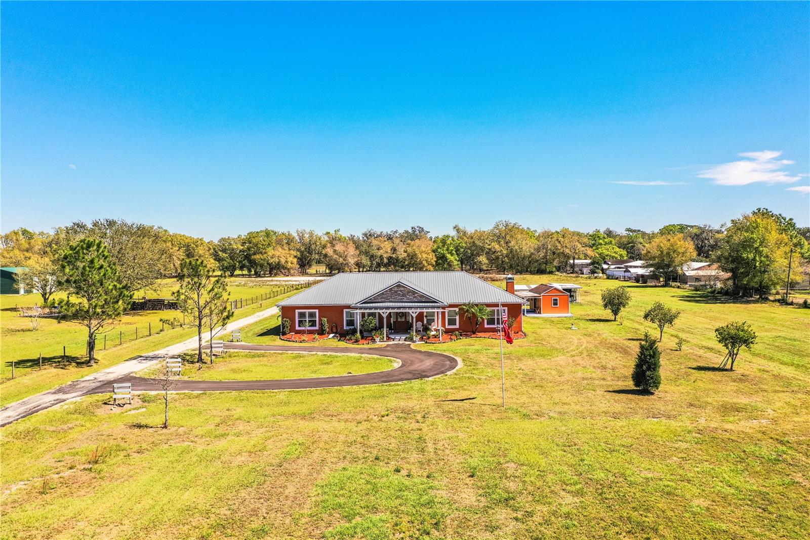 Over 5 acres of land an NO HOA! This type of property doesn't come around often. Behind a double gate entry, is a prepper’s paradise; a beautiful, 2017 custom-built home, with 3 bedrooms, 2.5 baths with 4 outbuildings. This property offers limitless possibilities with room for horses, farm animals, boats, RVs, ATVs and more! The home features gorgeous hardwood flooring, a grand foyer, and an open floor plan with 2,625 s.f. of living area. The large great room centerpiece is a wood-burning fireplace and a formal dining area for casual or intimate gatherings. The eat-in kitchen is finished with beautiful granite counters, hardwood cabinetry, an island with a prep sink, breakfast bar, brand new pot filler, custom backsplash, stainless steel appliances including double ovens, and a large walk-in pantry, a chef’s dream. The large primary suite features a tray ceiling with crown molding, French doors that provide access to the lanai and barn doors leading to a spacious 7'x9' walk-in closet and en-suite bath featuring travertine floors, a walk-in shower that doesn’t need a door or curtain, granite counters with dual sinks and makeup vanity, and a separate water closet for added privacy. The secondary bedrooms are good sized and share a Jack and Jill bathroom with separate granite vanities, travertine flooring, and a tub. Step outside onto the 825 s.f. covered and screened lanai, perfect for hosting holidays and parties, and creating memories with friends and family for years to come. A huge 30’x40’ barn with concrete flooring, electricity, and 2 attached horse stalls and tack room provides plenty of room for storage of tack equipment, vehicles, boats, ATVs and misc. equipment. A 20’x21' carport offers additional parking options. There is a she-shed, with electricity, that could be used as extra storage or an art or craft studio, as well as a DREAMY greenhouse with crystal chandelier lighting and operating antique windows for year-round plant growth, an oversized backyard chicken coop, and there is plenty of space for a large garden for growing fruits and vegetables. If living a self-sustained life is your dream, this property would be paradise. Even though it is not in a flood zone, the front yard retention pond provides plenty of drainage. Additional features include; a guest powder room, an interior laundry room equipped with a washer and dryer, new paint in bedrooms and second bath, double pane windows, metal roof (2017), 2 A/C units (2017), leased water softener from Atlantic Filter (paid monthly), deep well, on septic with its own pump station, rain gutters, (2)50 amp connections for RV or generator, underground electrical lines, new outdoor direct lighting on timer, stone accents, fully fenced and more. Located less than 1/2 mile from Highway 60, it makes for easy commutes to the east and west coasts of FL. Only 5 minutes from the new South Pointe Elementary School and less than 20 minutes from downtown Bartow, Winter Haven & Lake Wales. Whether you desire space for farm animals, horses, workshops, or just privacy, this property captures the essence of the rural living experiences you've always envisioned. Don't miss the opportunity to own this unique property; call today for a private tour!