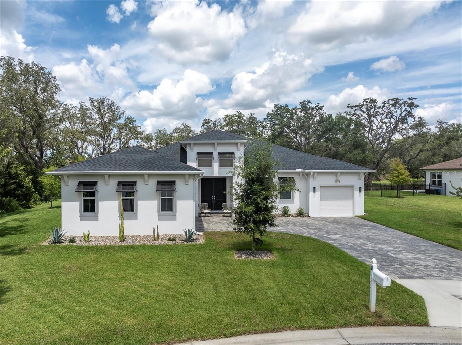 MODERN ONE STORY BEAUTY ON A PRIVATE .44 ACRE HOMESITE. Captivating DRB Homes formerly Biscayne Homes Bismark floor plan built in 2022 is the epitome of luxury living spanning 3,400 sqft including 4 brs, 3 ba + office, 3 car split garage is situated at the end of a cul du sac with only one neighbor affording wrap around privacy and views of the dreamy CONSERVATION in the gated community of Serengeti. The curb appeal is enhanced by the KEY WEST STYLE Exterior Elevation, 3 DIMENTIONAL SHINGLE roof, corbels, shutters, Paver driveway, Double Wood Front Door, manicured Landscaping and a welcoming front porch. As you enter the home, the grand foyer captures your attention accented by Modern Chandelier. Noteworthy after-market upgrades include LVP Floors in all bedrooms, custom lighting, EV charger, screened lanai and extended outdoor paver patio. To the right, a dedicated office provides functional space. As you enter the living room, a consistent Luxury Vinyl floor contrast by crisp white paint, create a bright and inviting space complimented by double tray ceiling, surround sound speakers, space for any furniture configuration and peaceful views. This Impressive gourmet chef’s kitchen combines refined timeless style w/ versatile functionality. Modern Shaker White wood cabinets are fashioned w/ crown, under cabinet lighting, Gold hardware & stylish backsplash. Expansive Island offers Britannica Cambria quartz waterfall counters, designer pendant lights, & space for 4 bar stools. Equipped w/ stainless steel appliances featuring built in oven/microwave, gas cooktop, modern chrome hood, dishwasher & refrigerator. Entertain with ease thanks to the wetbar with wine refrigerator and extra cabinets. A casual café dining space provides more seating and a tranquil view of the trees. The spacious Primary Bedroom features tray ceiling, ceiling fan and windows framing the views of nature. Luxurious ensuite provides a spa-like escape w/ dual sinks, soaking tub, oversized walk in shower and walk in closet w/ convenient breezeway to the laundry room. Well sized bedrooms 2 is located close to a full bath with tub shower combo while BR 3 & 4 are adjacent to bathroom 3 with dual sinks and tub shower combo. A unique multi-purpose storage room provides additional useful space. A covered and screened lanai offers the perfect escape to relax and enjoy the views of nature. An extended paver patio offers space for BBQ and dining alfresco while enjoying the privacy and views of the trees. *LOW HOA includes Cable, Internet and Trash* Serengeti is located near Publix, restaurants, Bishop McLaughlin High School with easy access to the 54 Mile Suncoast Trail for walking, biking and running enthusiasts & Veteran’s Expressway for quick travel to Tampa. Make this turn key home yours!