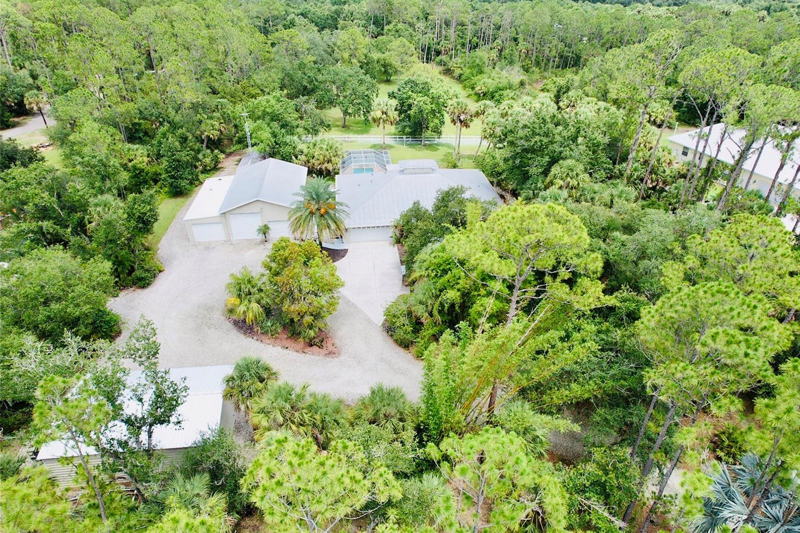 Looking for the perfect location to call home in the Country on 3 Acres with Multiple Garages/Workshops for Hobbies and Vehicles? Then you found it!!! Zoned AG, so bring your Horses to this beautifully cleared fenced-in back pasture! Newer Private Pool! Metal Roof! Just installed New Modem for the Gated Entrance…comes w/1 Year Warranty! Larger Workshop has a 10,000 lb. Car Lift, multiple Tool Chests, Industrial Fans and Upstairs Office! Downstairs has LED lighting for a pool table! 50’s Diner themed hang out area leads to separate room w/extremely bright lighting for working on vehicles! Also has mini Kitchen and Bathroom, Industrial Grade Air Compressor piped in to most areas of workshop, Climate controlled, Gorilla Garage Flooring, Insulated and Hurricane Rated! Newer Second Exterior Out Building has electric! Seller spent 15k for garage doors w/battery backup! Property has Mature landscaping & Bamboo!
This 4 Bedroom house w/Den Features a large Florida room for more space to Entertain! This home comes equipped with a whole house 25 kw Generator, 400 Gallon propane tank, whole house Shutters & the Oversized Front Porch has rollers that come down for protection from wind. Newer Leaf Guards on gutters, All New Interior Paint, Newer A/C, Septic pumped last year, Tile throughout, Office furniture can stay if buyer desires!