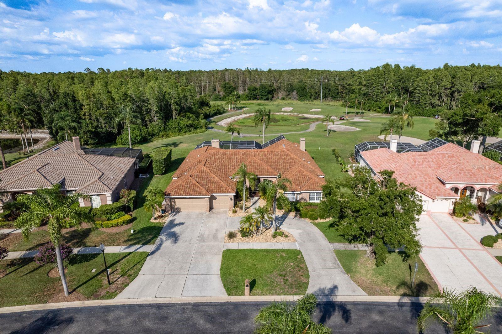 Welcome to this luxurious residence in the gated Crescent Oaks Golf and Tennis Club. One of the largest floor plans available, this home offers over 4,000 sq ft of refined living space. Freshly painted in 2024 and situated on one of the community’s premier lots, this stunning 5-bedroom, 4-bathroom home overlooks the 7th tee box and tranquil pond, creating the perfect Florida lifestyle experience. A 2016 tile roof, 2020 water heater, and dual A/C systems (2018 & 2022) ensure peace of mind, while the circular driveway and oversized 3-car garage add curb appeal and functionality. Inside, you’ll find vaulted ceilings, elegant crown molding, and tile flooring throughout, all bathed in natural light from expansive sliding doors that open fully for effortless indoor/outdoor living. The heart of the home is a chef’s dream kitchen featuring newer Samsung stainless steel appliances, an abundance of cabinetry, quartz countertops, and a large island overlooking the cozy family room with fireplace. The adjacent formal living area also opens wide to the lanai, ideal for entertaining. The owner’s suite is a true retreat with a fireplace, views of the pool, a large walk-in closet with built-in organizers, dual vanities, a luxurious soaker tub, and an impressively massive shower with dual rain showerheads. Additional bedrooms are nicely sized and have ceiling fans to keep guests or loved ones cool. A separate bonus suite offers its own living room, bedroom, and private bathroom—perfect for guests, in-laws, or multi-generational living, all with serene golf course views. Step outside to your private oasis—a huge screened-in lanai with travertine pavers, jacuzzi, and sparkling pool —the ideal setting to relax, entertain, or soak in the scenic views. Enjoy world-class amenities including tennis courts, pickleball, a country club, and championship golf course access—all within this exclusive, guard-gated community. This is Florida living at its finest—schedule your private showing today!
