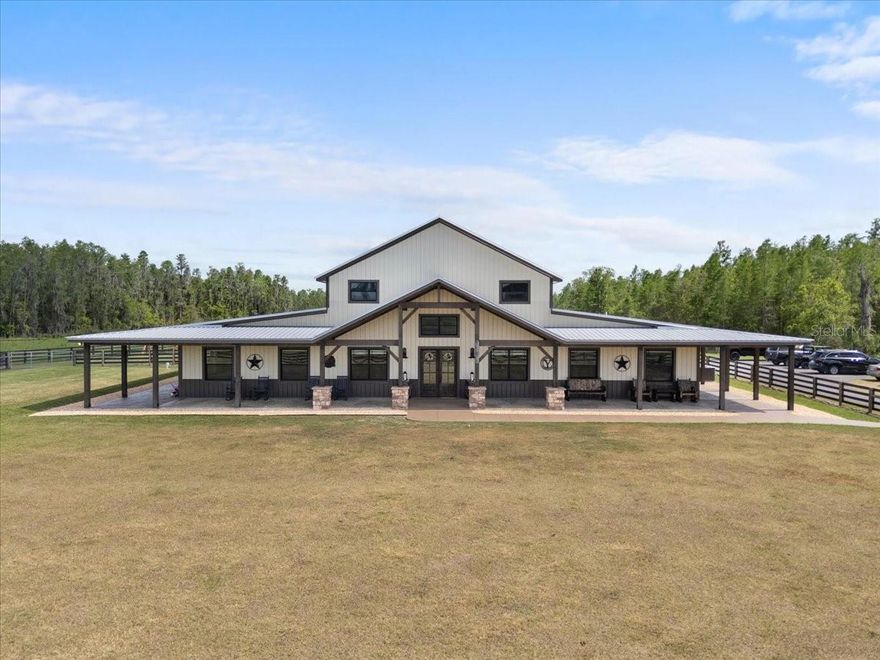 Welcome to Heaven on Earth — A Private Family Ranch Compound in North Lakeland. Tucked away on over 100 acres of improved pasture, scattered cypress heads, and multiple ponds this extraordinary family compound offers a rare blend of rustic luxury, multi-generational living, and serene Florida countryside. Abundant with wildlife including deer, turkey, and cows, this one-of-a-kind estate is the perfect setting for those seeking space, privacy, and endless possibilities. The Main House 11657 Moore Rd. (2023): Reminiscent of a traditional Barndominium, the main residence is a custom-built masterpiece with nearly 12,000 sq ft under roof (approx. 7,000 sq ft of living space). Constructed with block and poured concrete, metal siding, and designed for longevity, comfort, and function — this home is both ADA-compliant and visually striking. Inside, soaring ceilings with exposed wooden beams, an expansive open-concept kitchen with high-end stainless appliances, and a massive walk-in pantry make everyday living and entertaining effortless. The large island is ideal for hosting those large gatherings or simply serving your Sunday morning breakfast. The home features 5 bedrooms and 4 bathrooms, including dual primary suites connected by a luxurious Jack-and-Jill bathroom with a soaking tub and oversized shower. Two additional guest suites have private en-suite baths. A spacious mudroom and bonus utility room for storage, workspace, or pet accommodations. The true star of the show is the stone wood burning fireplace located centrally in the grand sized family room. A detached 588 sq ft bonus room (ideal for a game room, gym, or office) connects via covered breezeway and oversized carport, perfect for ATVs or full-size vehicles. Outside is an entertainers dream, enjoy a resort-style screened heated pool and spa with beach entry, fountains and amazing light features. The details in the expansive wrap around porch are simply amazing. From stamped concrete to tongue-and-groove ceilings, stone work and beautiful beams it truly is breathtaking. For added comfort this home does feature a full-property industrial-grade generator capable of powering the home for up to two weeks. 2nd Home 11651 Moore Rd. (2019): Privately set along the asphalt drive, this custom-built 3 bedroom, 2.5 bathroom farmhouse-style residence offers nearly 3,000 sq ft of living space. Designed with both comfort and style in mind, it boasts an entertainer’s kitchen with granite countertops and a large central island, a generous den/playroom, and pool-access half bath. Outdoors features a sparkling pool and spa with travertine decking and fenced yard. Metal roof and large carport complete this charming yet modern home. Additional Living Spaces & Structures: Free-Standing Two-Story Apartment: Loft-style barndominium with 1 bedroom, 1 full bath, full kitchen, washer/dryer, upstairs loft, open carport, and screened lanai. Workshop #1: Enclosed space with side attached open pole barn — perfect for storing farm equipment.  Workshop #2 with Luxury Apartment attached: Large shop with pole barn area and a brand new luxury two-story apartment with 1 bedroom, 1 bath, full kitchen, and loft. This estate is zoned agricultural with potential for additional dwellings under the ag exemption. Whether you’re looking for a working ranch, multi-generational homestead, or event-friendly destination, this property is a true legacy compound. Parcel 24-26-21-000000-031010 included in listing price.