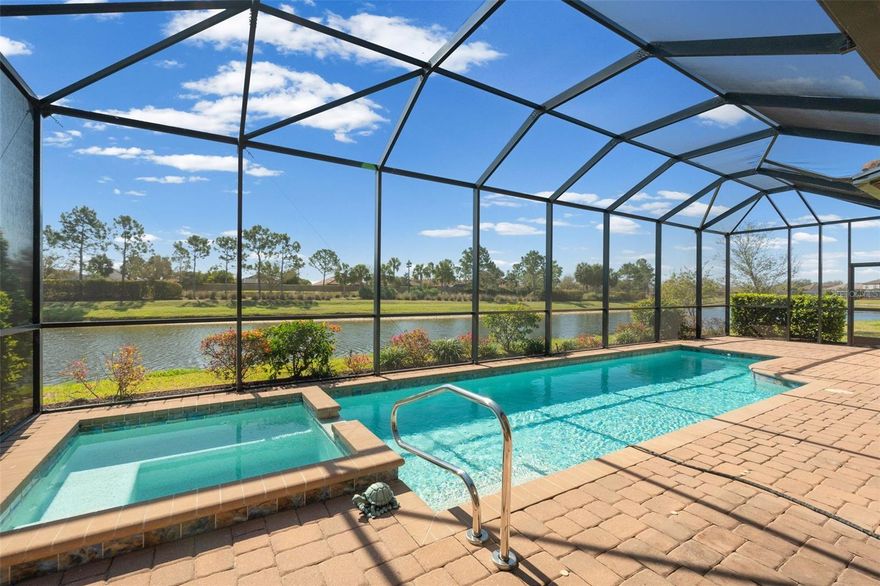 Looking for your very own piece of paradise? Step into this stunning Pallazio, designed with IMPACT windows and doors for your safety and ease, perfectly situated in the enchanting, maintenance-free community of Esplanade at Artisan Lakes. As you enter through the exquisite leaded glass double doors, an expansive open-concept floor plan bathed in natural light welcomes you. With soaring ceilings and elegant designer finishes, your eyes are irresistibly drawn to the magnificent back of the home, where a wall of glass pocket sliding doors invites the outside in, leading you to your own private outdoor haven. This space is undeniably the crown jewel, featuring a heated jetted pool and spa, a fully equipped outdoor kitchen, and a spacious screened lanai that overlooks tranquil pond views. Pool is designed with the BADU JET system, the ultimate in swimming resistance to enhance your swimming exercise. For your convenience lanai is protected with electric hurricane screens. 
Inside, the allure continues with tray ceilings, and crown molding that impart sophistication to every room. Custom lighting and fans in every living and dining area create a warm, welcoming atmosphere. For those with a culinary passion, the gourmet kitchen is a dream realized, featuring stunning quartz countertops, a spacious center island, upgraded cabinetry with convenient pull-out drawers, and sleek GE Café stainless-steel appliances, including a wall oven programmable for convection or air fryer, and a wine refrigerator.  This kitchen is expertly designed for both daily living and entertaining. The generously appointed living and dining areas flow seamlessly into your outdoor paradise, creating the perfect backdrop for gatherings.
 The owner’s suite serves as a serene retreat, outfitted with a spa-like bath and custom closets that blend style with practicality. Two additional bedrooms with custom closets and a versatile den present a myriad of possibilities for guests, a home office, or creative endeavors. Two plus tandem garage offers extra parking space or area for your hobbies or workshop. Garage is also wired with an EV charger hookup. Enjoy maintenance-free living, granting you access to two magnificent clubhouses and an events manager curating an array of social activities. The community boasts two resort-style pools, spas, pickleball and tennis courts, bocce ball courts, a gym, firepit, dog parks, and a playground.
 Conveniently located off I-75 and I-275, you’re just minutes away from the pristine Gulf Coast beaches, charming downtown areas, and an array of shopping, dining, and entertainment options. Whether venturing to Bradenton, Sarasota, Anna Maria Island, Ellenton Outlet Mall, St. Pete, or Tampa, this prime location allows you to fully embrace the best of Florida’s Suncoast.