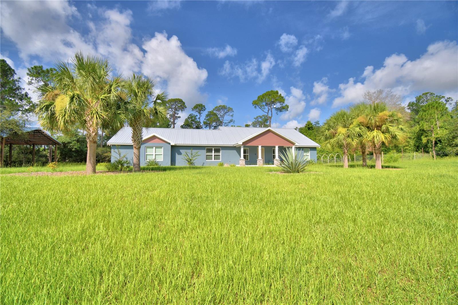 FLEXIBLE SELLER! Amazing home & Serene Paradise built in 2022. Easy 3rd Bedroom garage conversion currently a 2 BR 2 BA home with Lake Reedy Access. 7.58 acres of beautiful, natural Florida land, abundance of wildlife and access to bass fishing heaven & FAA approved for Seaplanes in Lake Reedy. Unique in so many ways. Horses are allowed according to the HOA but limits. Beautiful landscaping with palms, river rock and ornamentals welcome you to the front entrance. Exterior colors, along with columns accented with stone, draws you to rocking chairs and enjoy the serene natural beauty and sounds of nature. This stunning home offers over 3000 sq. feet under a metal roof. As soon as you enter the home you are greeted by the open perfectly designed floor plan with great room, dining room & amazing kitchen. Kitchen features granite counters that flow up for the back splash, deep sink, soft close drawers, GE stainless appliances, wood cabinetry & nice size island also with granite top. Crown molding accents this great area along with both bedrooms. Color scheme is crisp & bright, the luxury laminate flooring is gorgeous throughout the home. The hall from the kitchen to the garage takes you by the nice sized open shelved pantry & coffee bar & into laundry room where a granite countertop flows above the LG Thin Q washer & dryer making a perfect folding area and continues to and around the laundry sink. The master bedroom offers beautiful lighting and custom Bali blinds, ensuite master bath boasts of tile flooring, a walk in closet with shelving, tall counters with dual sinks and a very large ADA walk in shower with dual shower heads including a rain shower. Adjacent to the master thru French doors is a sunroom with a wall of windows and custom Bali blinds allowing the view of nature at its best and an entrance to the screened lanai. In this split floorplan the 2nd bedroom is like a 2nd master just beyond the living room/kitchen area. Oversized closet, dual access bathroom with large walk in shower, tall counters and granite make this perfect for the ensuite, guests or workshop in garage. The lanai can also be entered thru French doors off the dining room offering the perfect area to enjoy morning coffee or relax at the end of the day. Beyond the lanai a pan roof covers the outdoor kitchen area complete with brick pavers, sink, ceiling fan, gutters and room for a grill. Just steps away from the outdoor kitchen you will be amazed at the large brick paver area where the fire pit awaits. This area is perfect for quiet personal enjoyment or gatherings with friends and venturing down the cleared paths on the property or enjoying fruit from the orange, avocado or grapefruit trees. The garage is over 900 sq ft and designed for 3 cars. It has two garage doors so has plenty of room for golf cart or motorcycles, etc. and work space. Some of the Kobalt cabinets shown are staying as well as a mini split AC unit. The 40 X 30 concrete floor pole barn has electricity and water is nearby as well as a storage shed. Lake Reedy is known as one of the best fishing lakes in this area. This home not only has access to lakefront on Lake Reedy but you also have access to the public boat ramp that is a nice ramp with floating dock, restrooms and not far away. Don't miss out on this one. Schedule your private showing today and make this your forever home. ***These photos show it furnished. It is not furnished any longer***