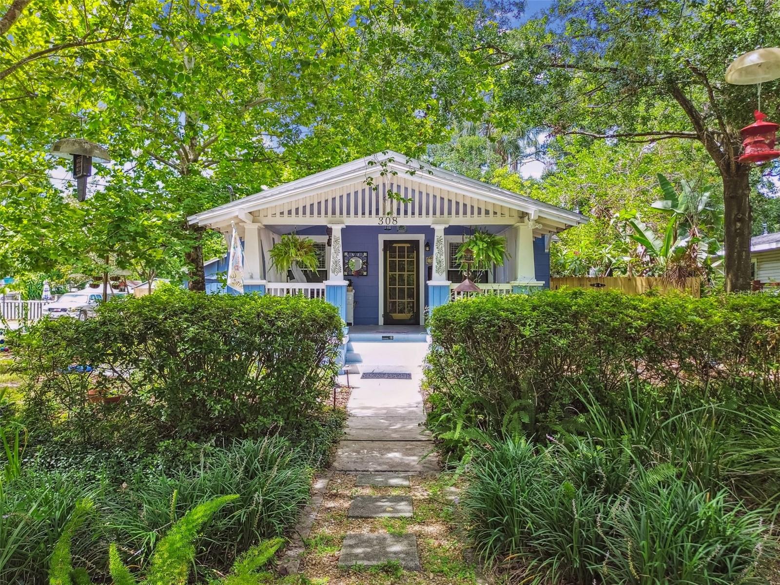 Charming 1920s Bungalow in the Heart of Historic Seminole Heights. Step into timeless character and thoughtful updates with this beautifully maintained 1920s bungalow, located in the highly sought-after Seminole Heights historic district. Proudly only the second owner, this classic 2-bedroom, 2-bath home offers just over 1,100 sqft of inviting living space filled with warmth and authenticity. From the moment you arrive, the large front porch with its classic swing welcomes you home—perfect for morning coffee or evening relaxation. Inside, original heart of pine floors, refinished just five years ago, add richness and charm throughout. Cozy up by the wood-burning fireplace or unwind in one of the two vintage-style bathrooms, both featuring clawfoot tubs that reflect the home’s historic roots. The primary suite includes an en-suite bathroom and walk-in closet—an unexpected and thoughtful feature for a home of this era. Additional highlights include a dedicated inside laundry area, a gas tankless water heater for endless hot water, and a detached garage building ideal for a workshop, studio, or extra storage. The beautifully landscaped side and backyard are a gardener's paradise, with lush plantings and serene water feature ponds that attract birds and butterflies. Located directly across the street from the Seminole Heights Garden Center, and just minutes from I-275, downtown Tampa, and the beloved restaurants, cafés, and shops along Florida Ave and in “The Heights.” Don’t miss your opportunity to own a lovingly cared-for piece of Tampa’s history in one of its most vibrant and cherished neighborhoods.