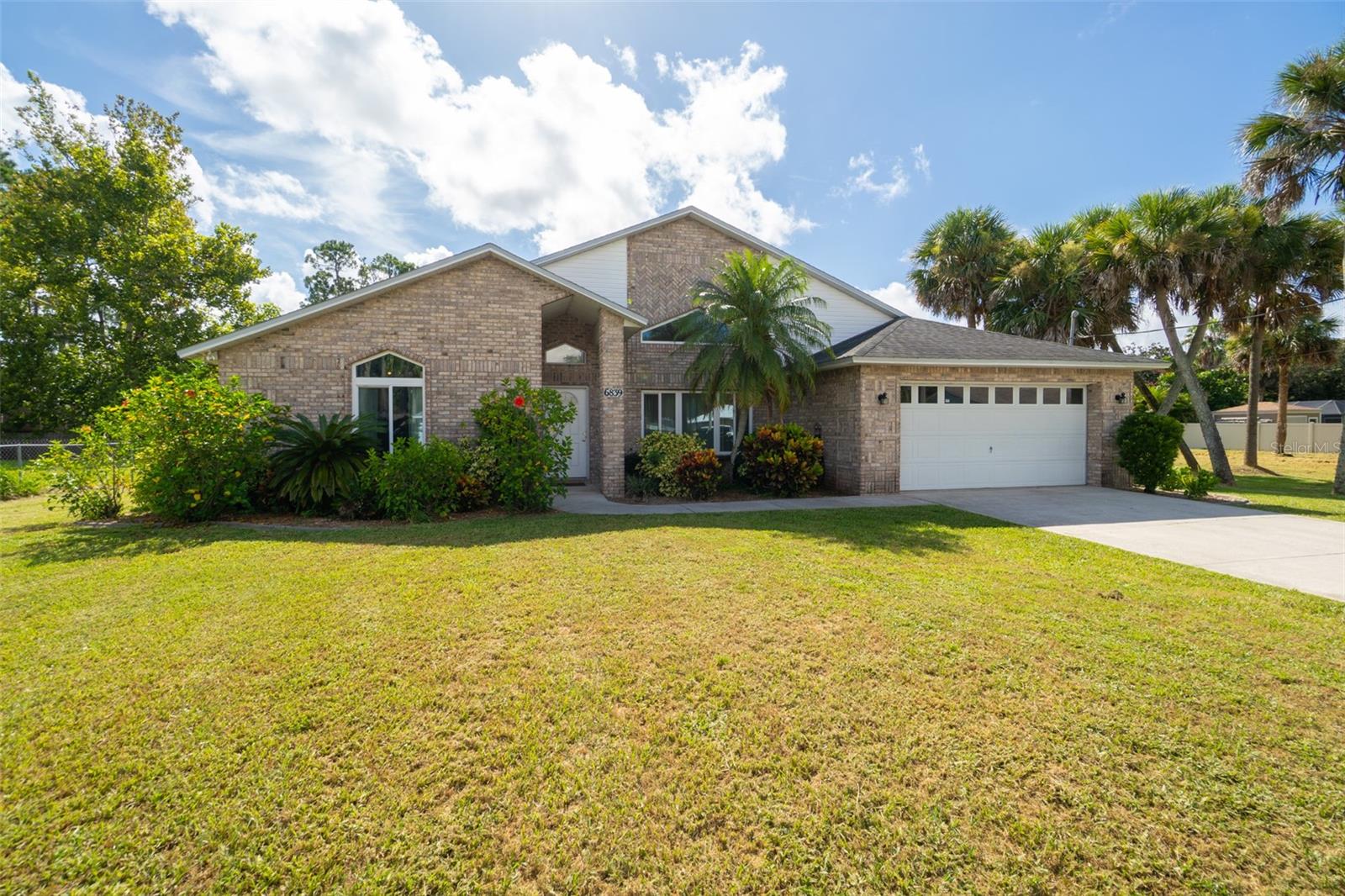 Welcome to this meticulously maintained 4-bedroom, 2-bath home with NO HOA and exceptional pride of ownership! Featuring a light-filled kitchen with granite countertops, wood cabinetry, and newer appliances. Both bathrooms are tastefully renovated with granite vanities and tiled showers. Enjoy two spacious living areas, perfect for entertaining or relaxing with family. Skylights and new LED recessed lighting brighten every corner, complemented by brand new carpet and luxury vinyl plank flooring. Major upgrades include a new AC unit (2020) and impact-rated windows (2018). Step outside to a screened-in porch overlooking a large backyard, ideal for BBQs, hobbies, or adding a pool. No neighbor on one side, thanks to an adjacent empty lot, offering added privacy. Oversized 2-car garage provides ample storage. Conveniently located near I-95 and the Beachline for quick access to beaches, the airport, and Orlando attractions. Move-in ready and packed with value!