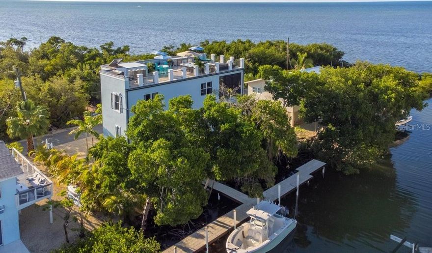 Sunrise and sunset will never be the same when you experience the open ocean views from either the second floor balcony or the unbelievable rooftop party deck! We highly recommend that you review the 4 professional videos that have been produced. These videos will be happily included with the sale of the home which will greatly enhance the new owner's ability to market this property for prospective short term rentals. With SO many great spots to check out, this location is magical. Marathon even has its own regional airport, which should appeal to any pilots looking to experience the Florida Keys lifestyle. This 4-bedroom, 3-bathroom canal front home with elevator and rooftop party deck is being sold completely furnished and ready for vacation rentals or if you'd like, you can move right in! Panoramic ocean views from Key Colony to Sombrero Beach. 75' of protected, no maintenance dockage. Direct boating access to the Atlantic, just minutes from Sombrero Light house or to the Gulf of Mexico under the 7-Mile Bridge. This home features reinforced concrete construction, impact windows/doors and tile roof to withstand the elements of living on the water. Designed for open concept living with bedrooms on their own level for added privacy! Chef's kitchen with massive island, incredible cabinetry and storage space. Privacy and panoramic bird's eye view from the expansive 1,275 sf rooftop deck, complete with an outdoor kitchen, ice machine, sink, hot tub, umbrellas and firepit. Protected on the east side by 8 acres of non-buildable, natural habitat. Weekly vacation rentals are permitted in this neighborhood. The owners have added an outdoor entertainment area with a second hot tub and lots of games for your guests to use. There is even a kitchenette in the lobby with an ice maker, fridge and wine cooler. They have literally thought of EVERYTHING!