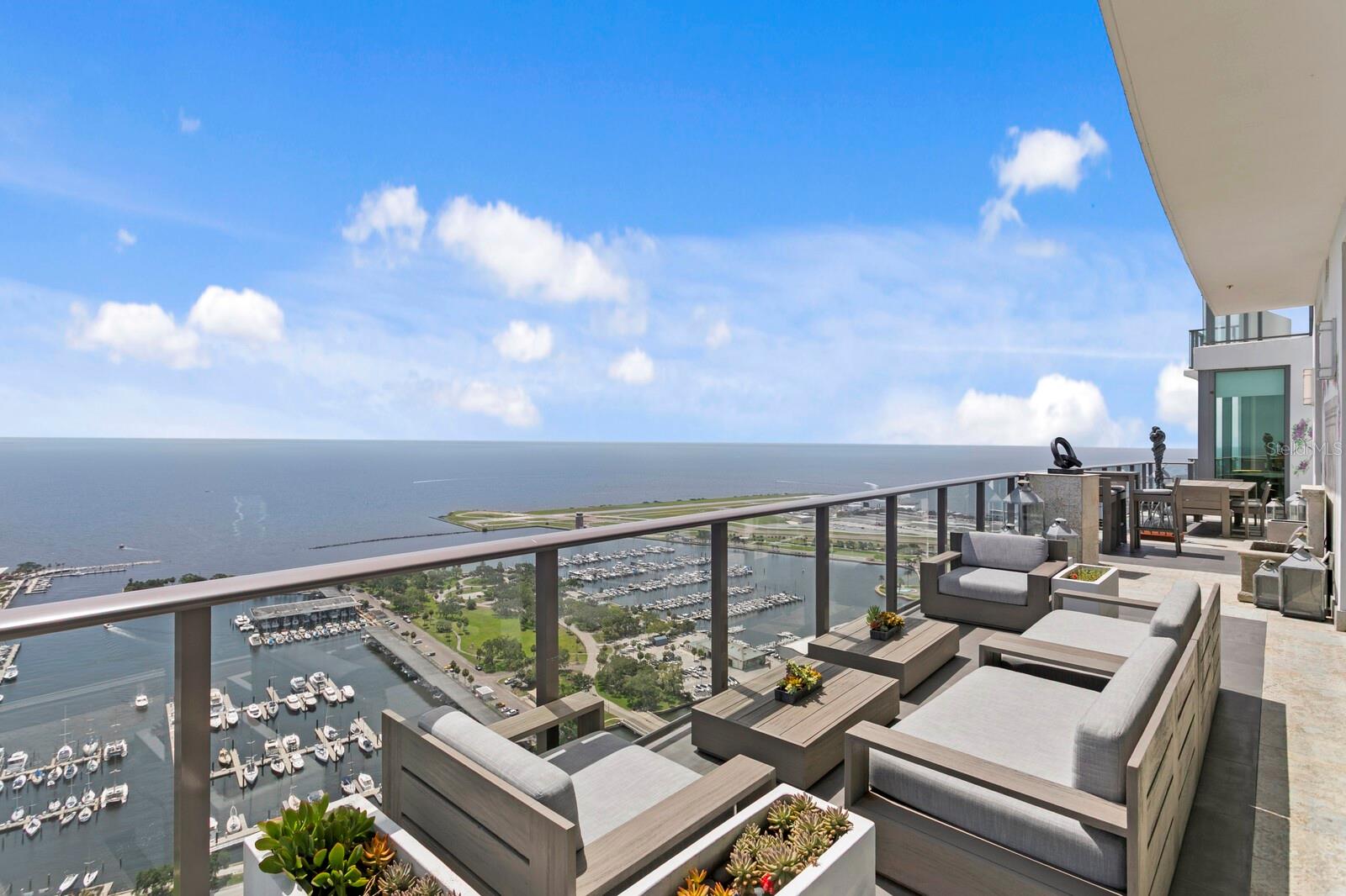 UNPARALLELED PENTHOUSE SANCTUARY | THE SKY COLLECTION AT THE ONE IN DOWNTOWN ST PETE | This is not merely a residence—it's a statement. Exclusively crafted by combining two premium units during the building’s construction, this extraordinary penthouse represents the pinnacle of luxury living in downtown St. Petersburg. Perched on the 39th floor, this one-of-a-kind sanctuary offers the most coveted panoramic views of Tampa Bay through floor-to-ceiling windows that frame the endless horizon. This residence lives like a single family home with 11’ ceilings and amenities that you would only typically find in a home. Culinary Excellence Redefined | The chef's kitchen stands as a masterpiece of form and function, featuring an oversized waterfall island with stunning 2.5-inch Sapienstone countertops that flow seamlessly into a matching backsplash. Exquisite imported NAC-crafted cabinetry provides both beauty and superior functionality throughout. Every detail has been meticulously considered: Jenn-Air double panel refrigerators, a Jenn-Air Euro Style Series double oven, a premium Rohl sink, and a full butler's 2nd kitchen that can be completely hidden from the main living area which also has its own private entrance for easy catering and deliveries. The sophisticated bean-to-cup Miele coffee machine and built-in Miele wine refrigerator positioned perfectly off the dining area ensure effortless entertaining at the highest level. Master Suite Wellness Sanctuary Retreat | Take in your private haven featuring soaring high ceilings and an oversized master closet with custom cabinetry expertly crafted by California Closets and NAC, creating a sophisticated storage solution that rivals the world's finest boutiques. The spa-inspired master bath becomes your personal age-rejuvenation center with dual vanities featuring premium Grohe fixturing, a luxurious soaking tub, and an oversized shower complete with a Steamist steam system and a unique built-in cold plunge tub. This extraordinary combination of therapeutic heat and invigorating cold therapy offers the ultimate in wellness and anti-aging benefits, creating your private longevity sanctuary. The Kohler smart toilet reflects the attention to innovative luxury throughout. Unmatched Privacy & Outdoor Living | As the building's only recessed unit, this penthouse provides an unparalleled sense of privacy and exclusivity. Rollease Acmeda motorized shades with remote controls offer effortless light control while maintaining those stunning vistas. The expansive 600-square-foot wrap-around terrace—the largest in the entire building—becomes your private sky deck, complete with curated designer furnishings and an elegant fountain, creating an outdoor oasis suspended above the city. Sophisticated Living Spaces | Every room showcases globally-sourced designer furniture, finishes, fixtures, including 3 stunning Murano chandeliers. A premium Sonos sound system provides seamless audio throughout, while four Samsung Frame TVs blend technology with aesthetics. Refined Guest Accommodations | Guest bathrooms showcase elegant marble flooring and feature Villeroy & Boch commodes with premium Grohe fixturing, ensuring every visitor experiences the same level of luxury. Turnkey Luxury | Available partially furnished with select exclusions, this residence allows you to simply arrive and begin living at the highest level. This is more than a home—it's your signature in the sky.