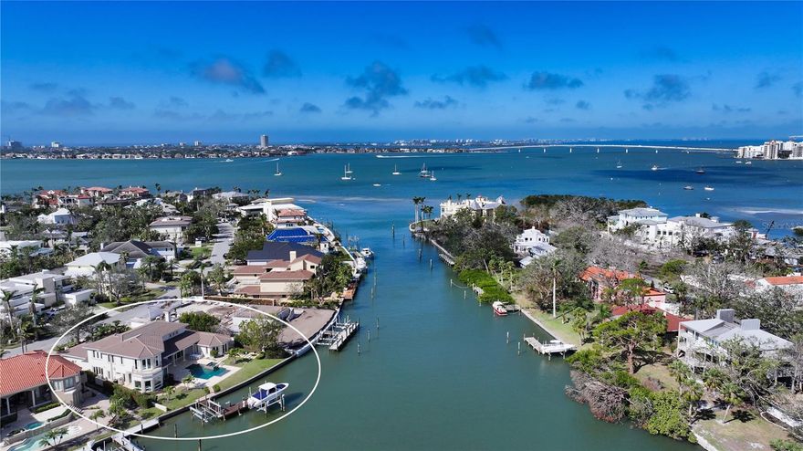 Step into a world of waterfront luxury with this furnished five-bedroom Harbor Acres estate, perfectly positioned along a yacht basin with unobstructed access to Sarasota Bay. A travertine walkway, accompanied by a charming fountain, newer roof, and double-door entry, sets the stage for a grand welcome. Inside, architectural craftsmanship is evident in every detail, from crown molding and tray ceilings to new impact glass windows, French doors and sliding doors throughout that create seamless indoor-outdoor living. The first floor is designed for both features stunning porcelain tile flooring that connects the open layout. The living room, with its inviting fireplace, opens to the pool deck through pocketing sliders, allowing for plenty of natural light. The formal dining room is framed by sliding doors on two sides that open to serene atrium spaces and leads directly into the convenient Butler’s pantry. Steps away is the chef’s kitchen that’s as functional as it is stylish, overlooking the family room and seamlessly extending to the outdoors through glass doors. Granite countertops and tile backsplash add sophistication, while an island, wraparound breakfast bar, additional walk-in pantry, built-in oven, warming drawer, gas cooktop, and ice maker cater to culinary enthusiasts. The primary suite, located on the main floor, is a private retreat with French doors opening to the lush waterfront. The spa-inspired bath is adorned with travertine tile, split floating vanities, private water closet, soaking tub, and two glass showers. A huge walk-in closet with built-in shelving, an island, and a dressing area enhances the suite’s luxuriousness. The second floor offers a balance of comfort and functionality, with a versatile media room featuring custom built-ins, wet bar, plantation shutters, and wood flooring. The four generously sized guest bedrooms on this level provide the perfect amount of privacy for overnight visitors. The largest of these guest quarters is the waterfront bedroom suite boasting an oversized walk-in closet and French door access to a private balcony. The outdoor spaces are designed for relaxation and entertaining. An expansive travertine pool deck includes covered sitting areas with ceiling fans, a sparkling pool, and raised heated spa. Boating enthusiasts will appreciate the 119 feet of water frontage, and private L-shaped dock with multiple lifts. Situated in one of the region’s most coveted waterfront communities, this home is just minutes from the fine dining, boutique shopping, and cultural attractions of downtown Sarasota and St. Armands Circle. Nearby, the pristine shores of Lido and Longboat Key invite sun-soaked days on the Gulf, while championship golf courses and world-class marinas offer endless recreational opportunities. This is an opportunity to experience coastal luxury at its finest, where impeccable design meets an unparalleled waterfront lifestyle.