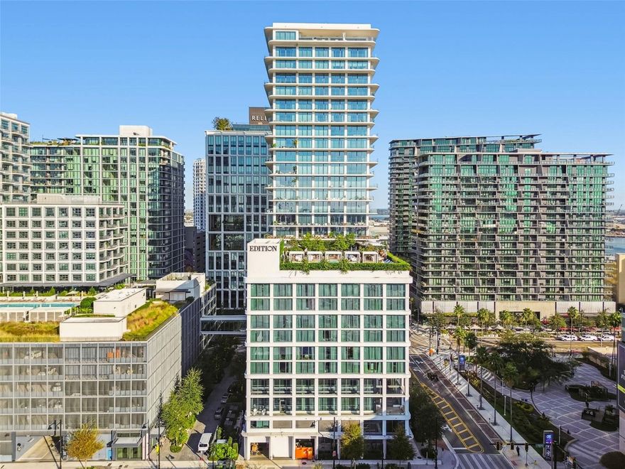 Discover an unrivaled living experience at The Tampa EDITION Residence 2202, a sophisticated corner unit masterfully designed and framed by sweeping vistas of Tampa Bay, the sprawling downtown skyline, and the visionary Water Street development. This residence, completely furnished and inclusive of all utilities, epitomizes refined urban luxury. The exquisite open floor plan flows seamlessly between living, dining, and entertaining spaces, designed to offer an unparalleled experience of comfort and elegance. The private primary suite serves as a luxurious retreat, complete with a spa-inspired bath clad in Polaris White marble, a freestanding Kaldewei soaking tub, a custom double vanity, and ambient lighting that enhances its serene atmosphere. This sanctuary also includes a custom walk in closet and direct access to a wrap-around terrace with breathtaking views. An additional bedroom, equipped with its own ensuite bath, provides sophisticated accommodation for family or guests. Every element of this home reflects meticulous craftsmanship and elegant design. Expansive floor-to-ceiling windows flood the 10-foot-ceiling interiors with natural light, seamlessly blending indoor and outdoor spaces. Sliding glass doors from each room open to generous wraparound terraces adorned with post-less glass railings, offering uninterrupted views of the city below. Thoughtfully curated details include 10-inch custom Grato white oak floors, Polaris White marble countertops with a waterfall island and full-height backsplash, ambient cove lighting, and custom Molteni white oak cabinetry. The state-of-the-art Gaggenau kitchen features a wine cooler, five-burner gas cooktop, and a discreetly integrated Miele vented hood. As part of The Tampa EDITION, residents enjoy exclusive access to an array of five-star amenities envisioned by legendary hotelier Ian Schrager. From award-winning dining experiences led by celebrated chefs to the rejuvenating full-service spa, each offering embodies EDITION’s dedication to world-class living. The rooftop pool and terrace provide a tranquil escape with panoramic city views, while residents-only spaces, including a private gym, social kitchen, and lounge, create an ambiance of refined exclusivity. Complete with two dedicated parking spaces, private storage room and 24-hour concierge, this residence anticipates every need. Nestled within Water Street Tampa, the world’s first WELL-certified community, The Tampa EDITION is the ultimate intersection of wellness, innovation, and sophistication. Residence 2202 invites you to experience an elevated lifestyle unlike any other in Tampa.